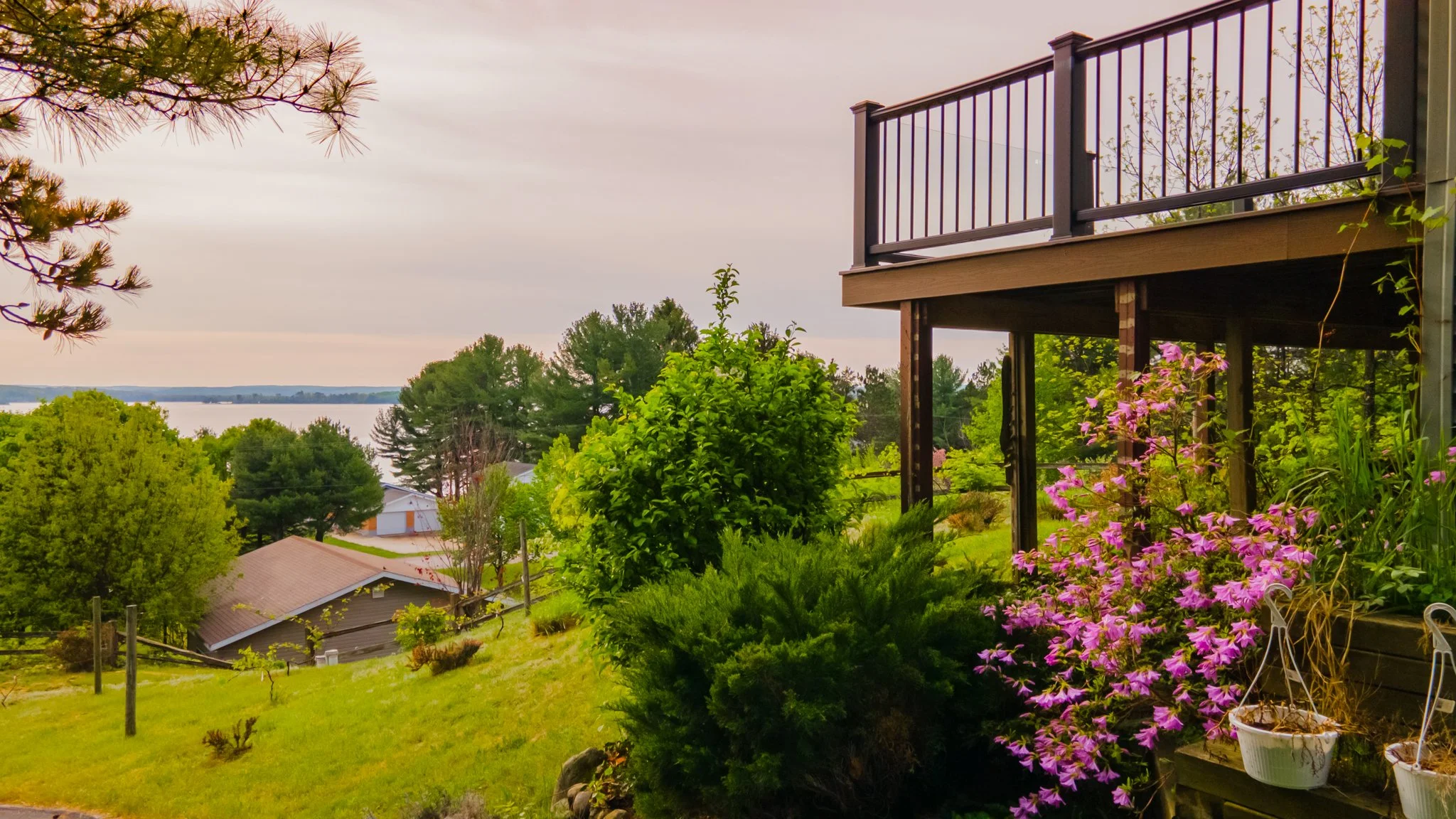 Lush garden beside a house overlooking a lake at sunset