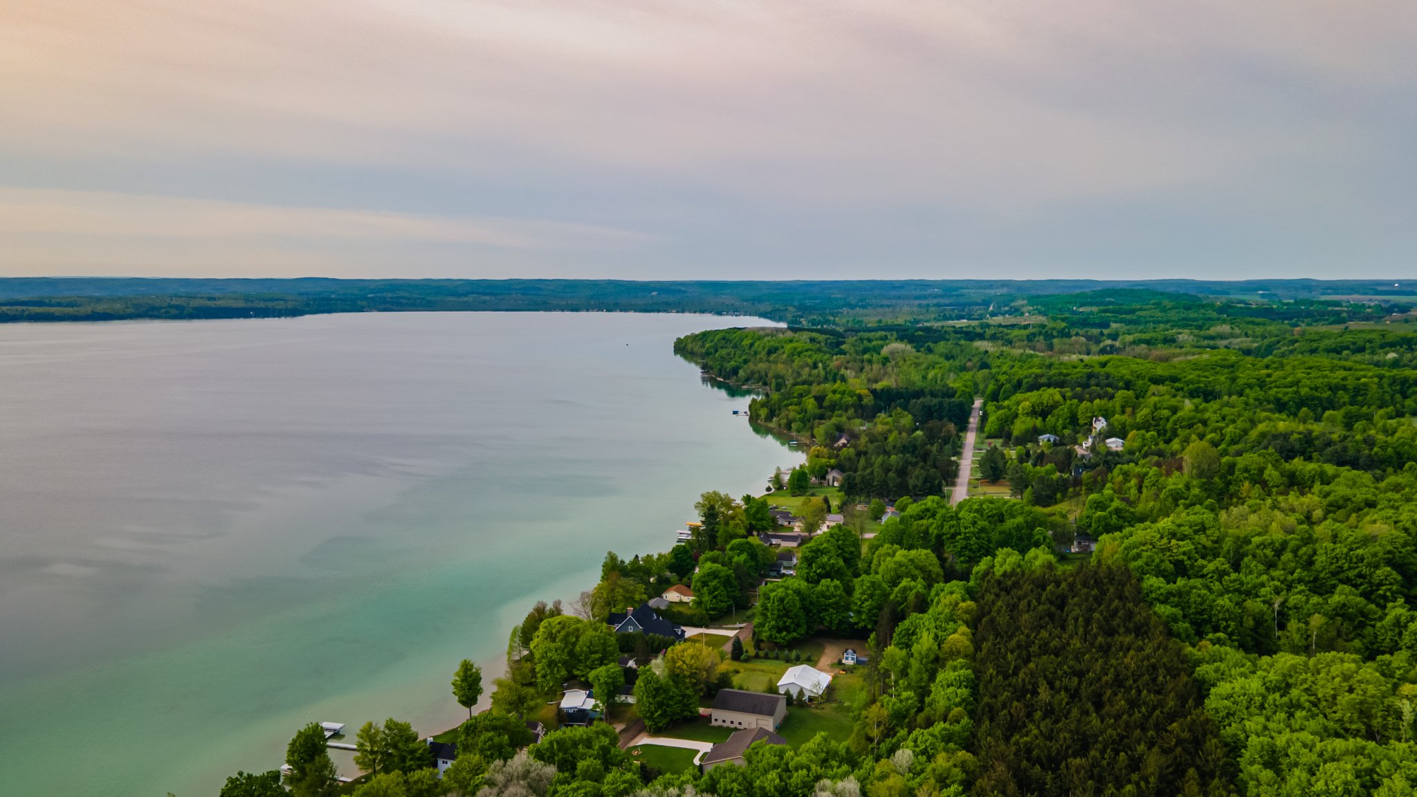 Aerial view of a lakeside neighborhood surrounded by lush green forest under a cloudy sky
