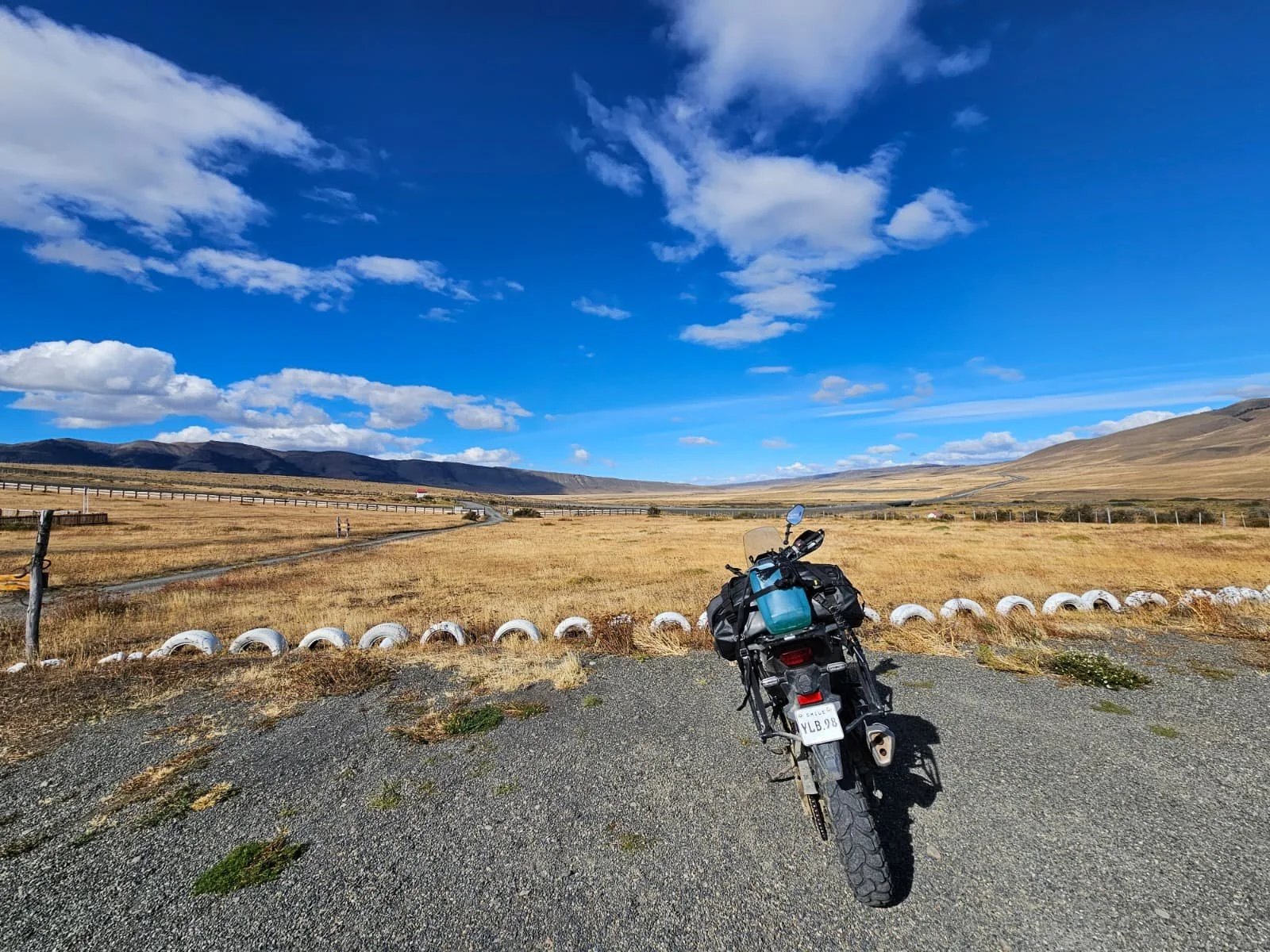 ADV motorcycle facing the golden hills under a bright blue sky.