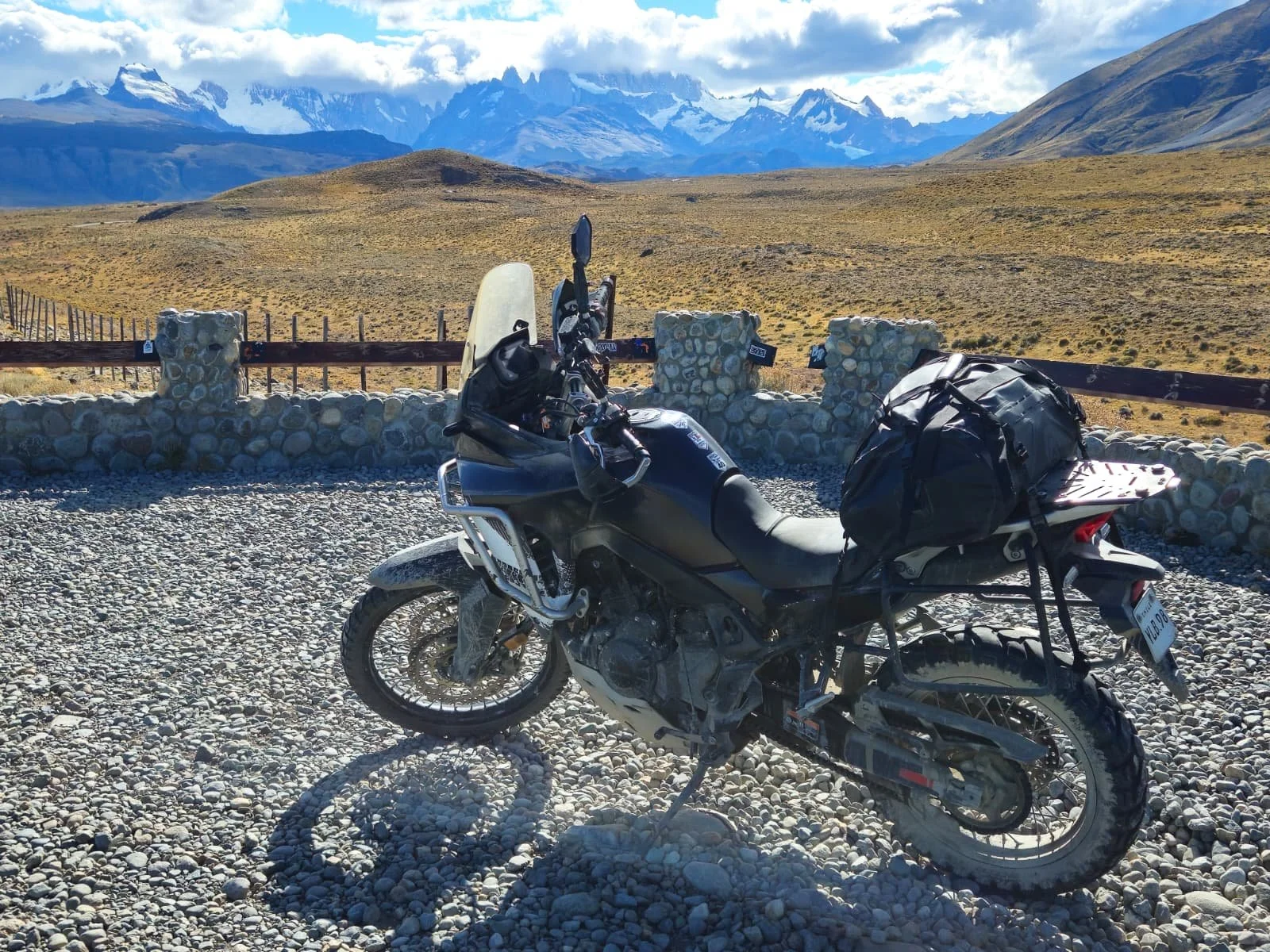 ADV motorcycle parked on gravel with view on El Chalten mountains in the distance.