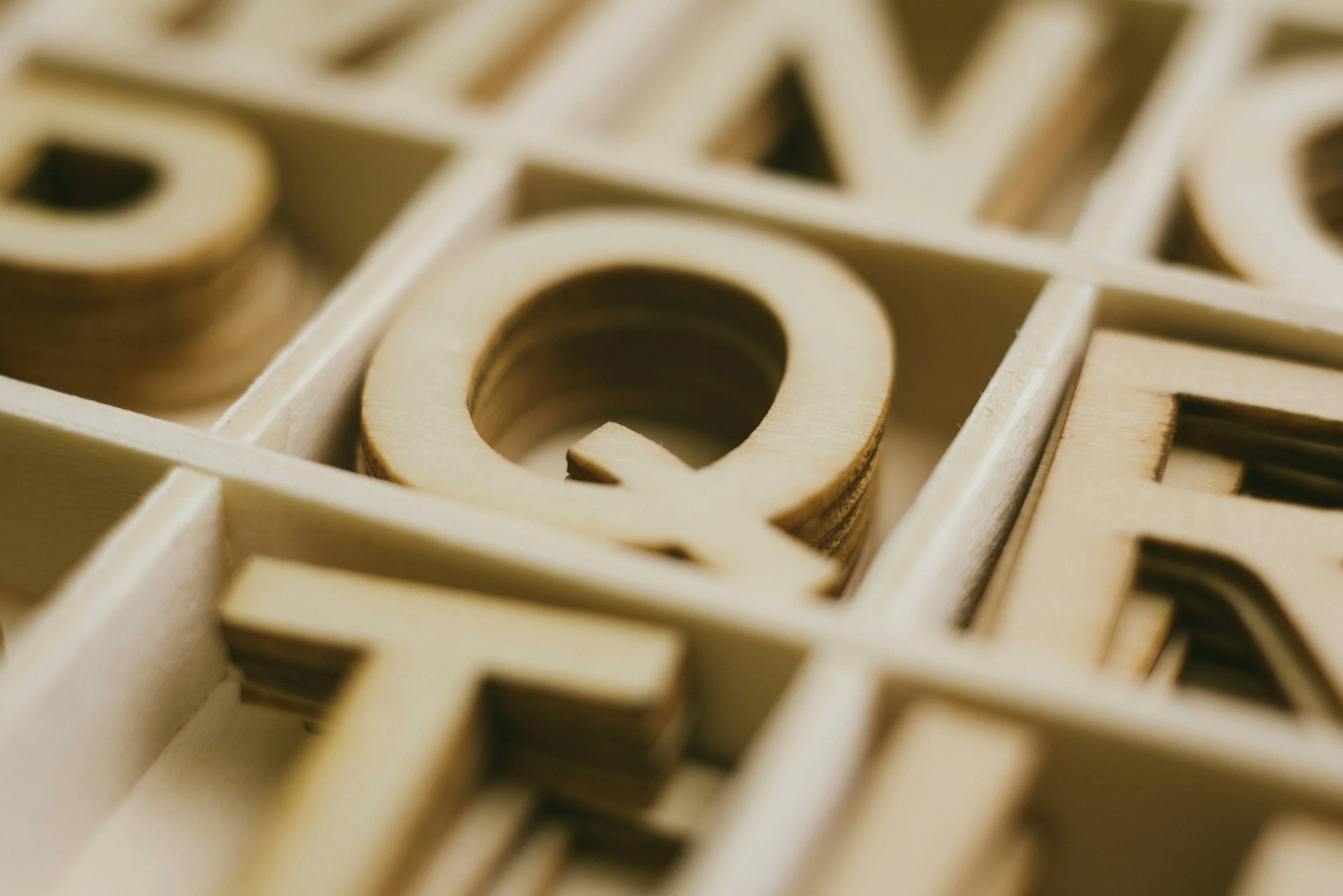 Close-up of wooden letter cutouts arranged in a grid pattern.