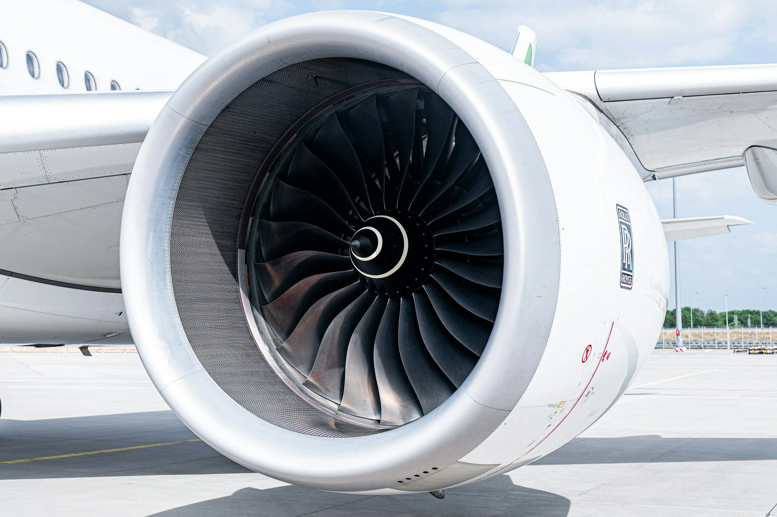 Close-up of a Rolls-Royce jet engine on an airplane at an airport.