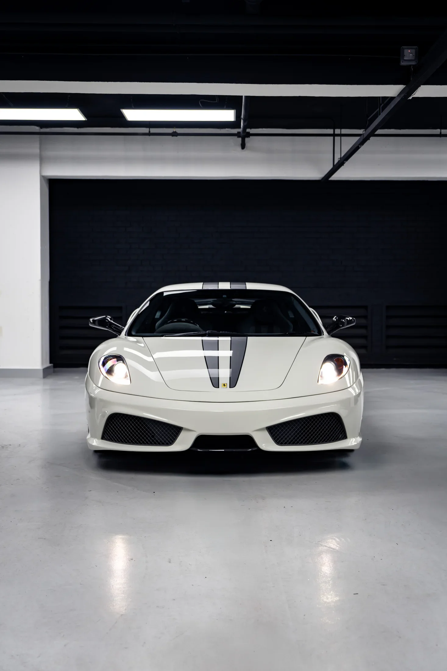 Ferrari 430 Scuderia in Bianco Avus — With dark stripes inside a garage — AKC Asset Management.