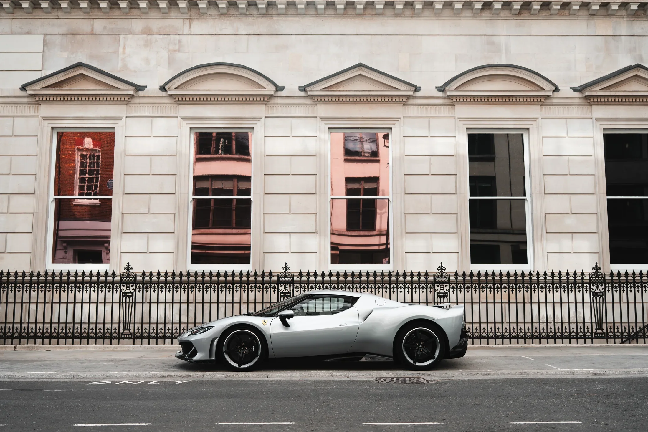 Ferrari 296 Speciale in Argento Nürburgring — Parked beside a classical building — AKC Asset Management.
