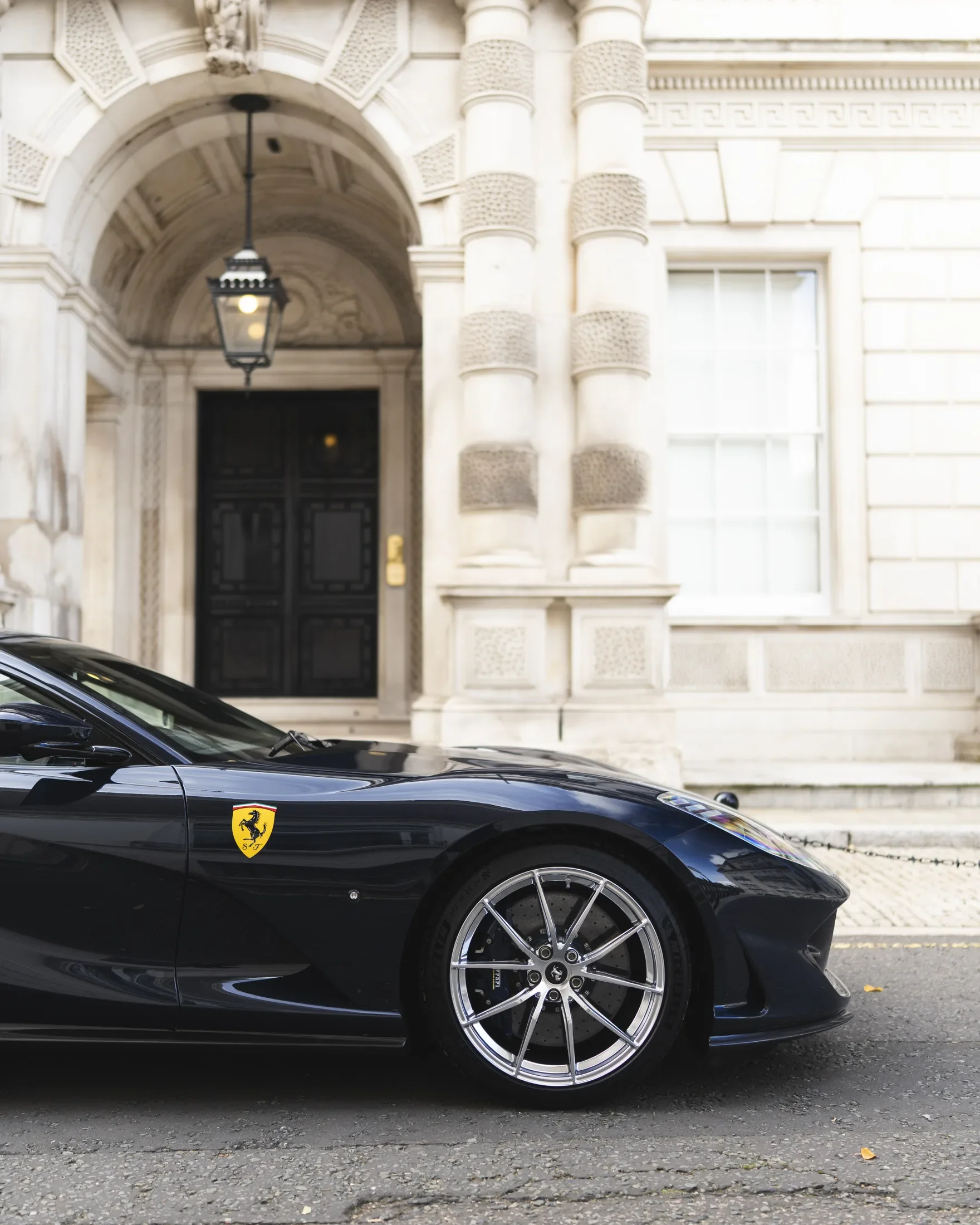 Ferrari 812 Superfast in Blue Pozzi — Side profile beside a stone entrance — AKC Asset Management.