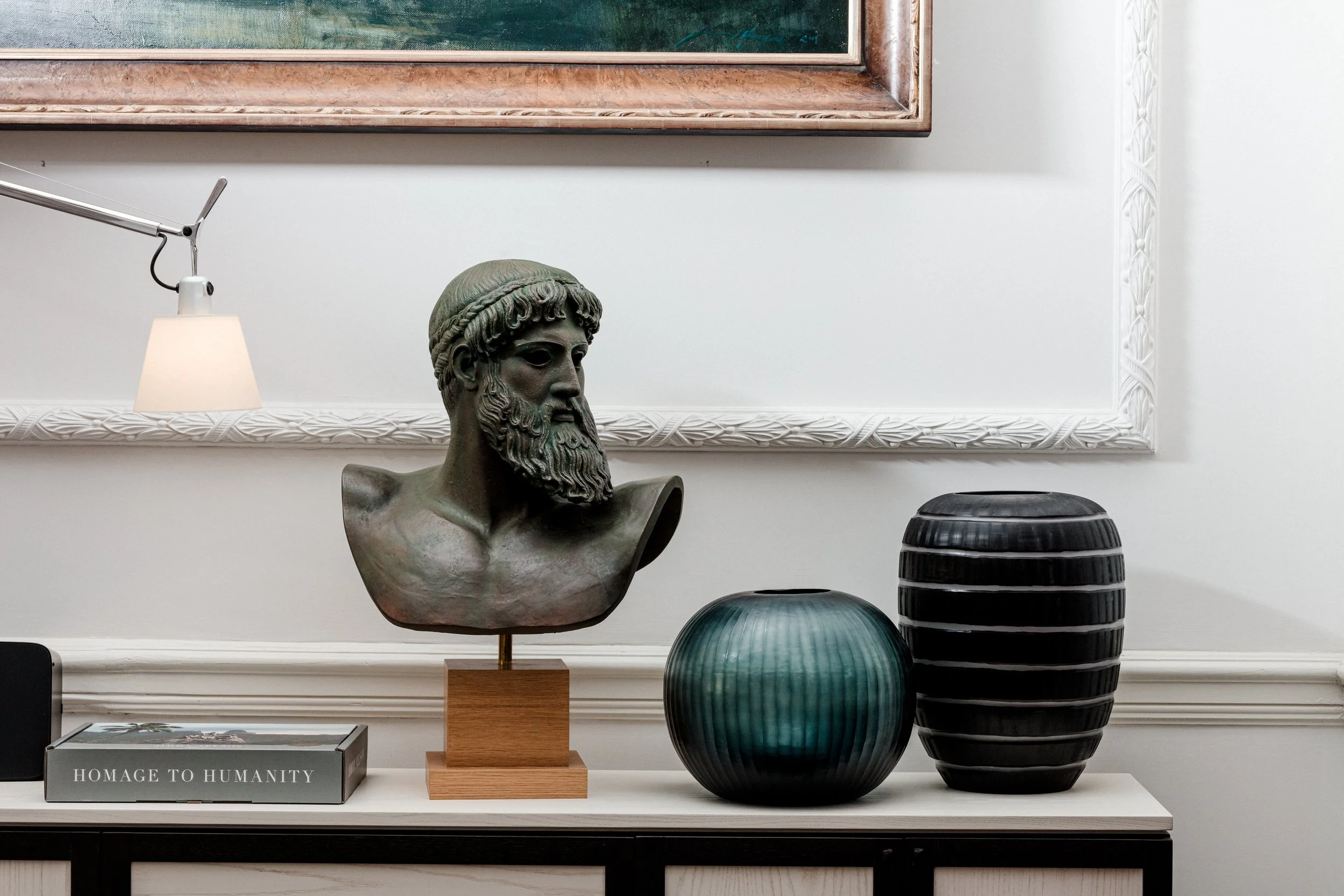 Bronze bust and decorative vessels displayed beneath a framed artwork — AKC Asset Management art collection services.