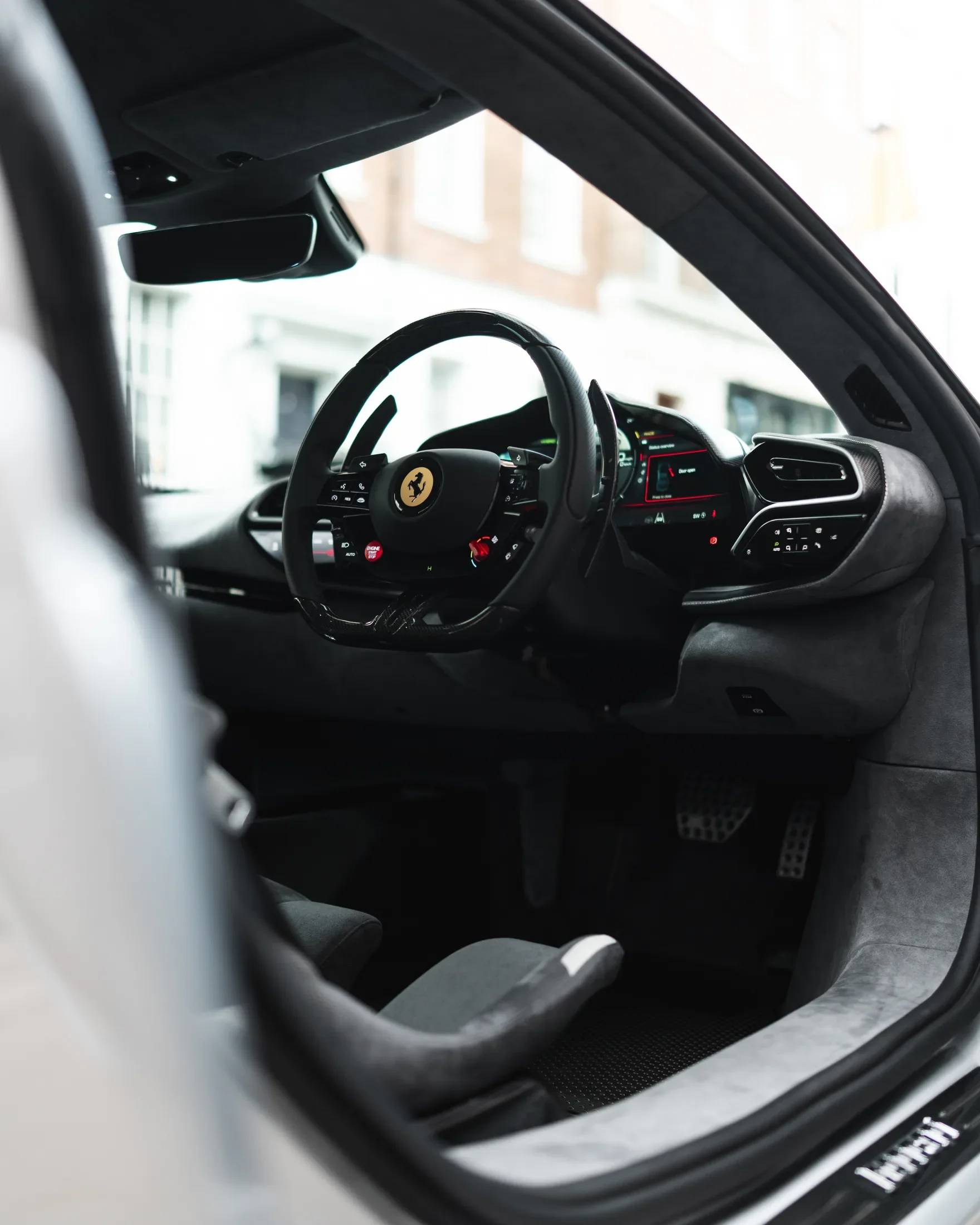Ferrari 296 Speciale in Argento Nürburgring — Steering wheel and instrument panel through an open door — AKC Asset Management.