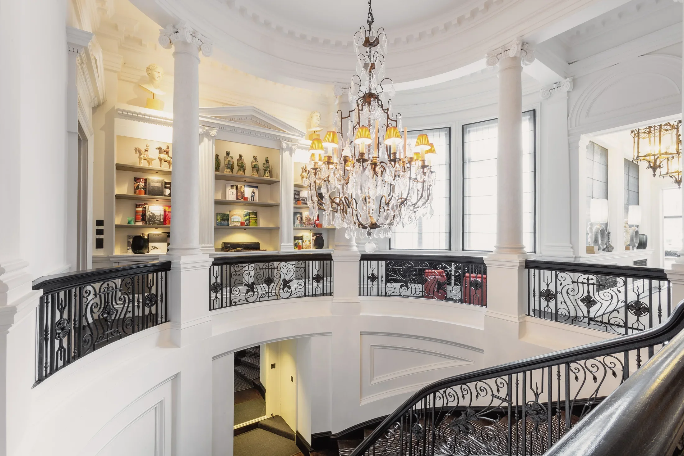 Chandelier above a curved staircase and decorative balustrade — AKC Asset Management real estate, part of AKC Group.