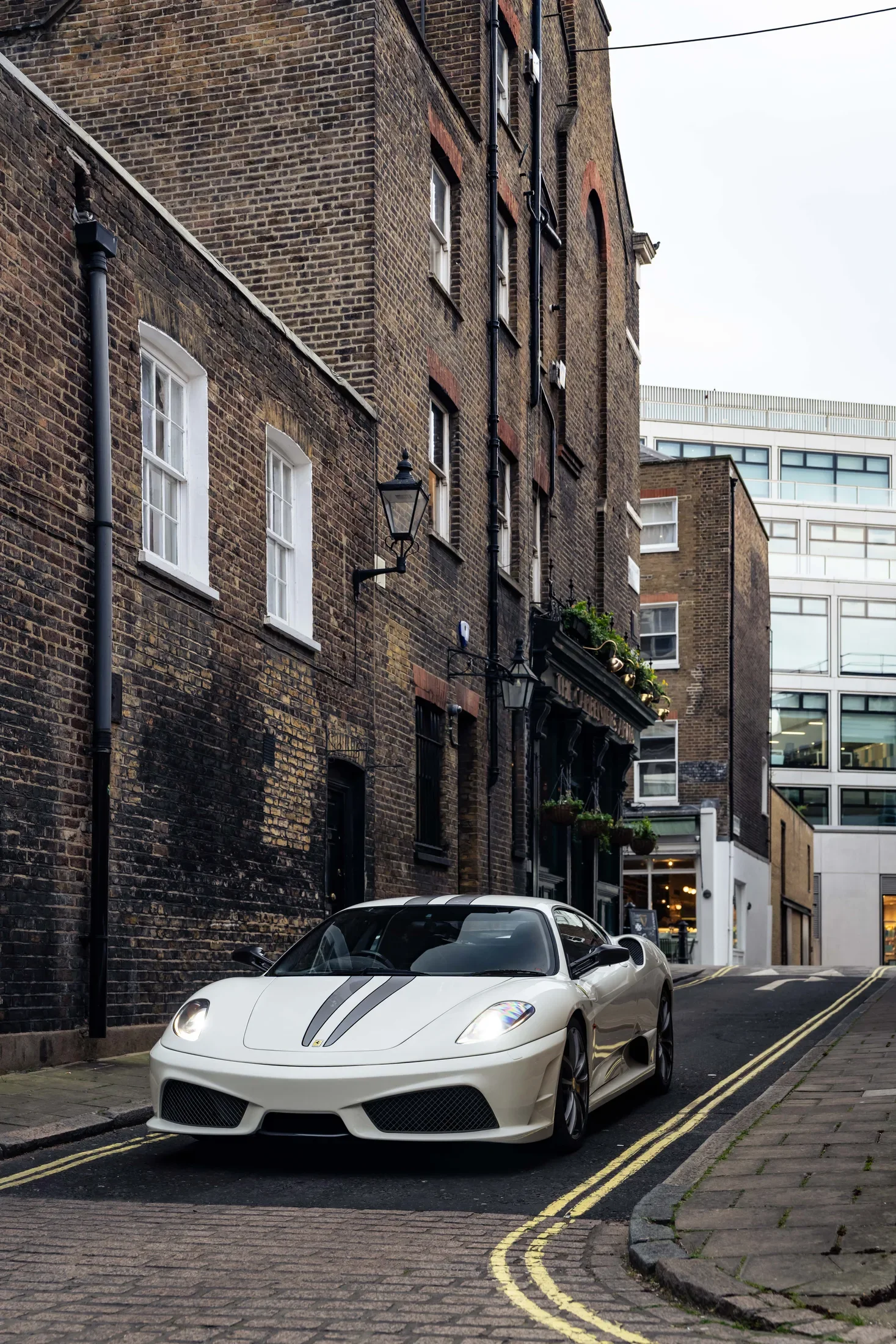 Ferrari 430 Scuderia in Bianco Avus — Front three-quarter view on a narrow street — AKC Asset Management.