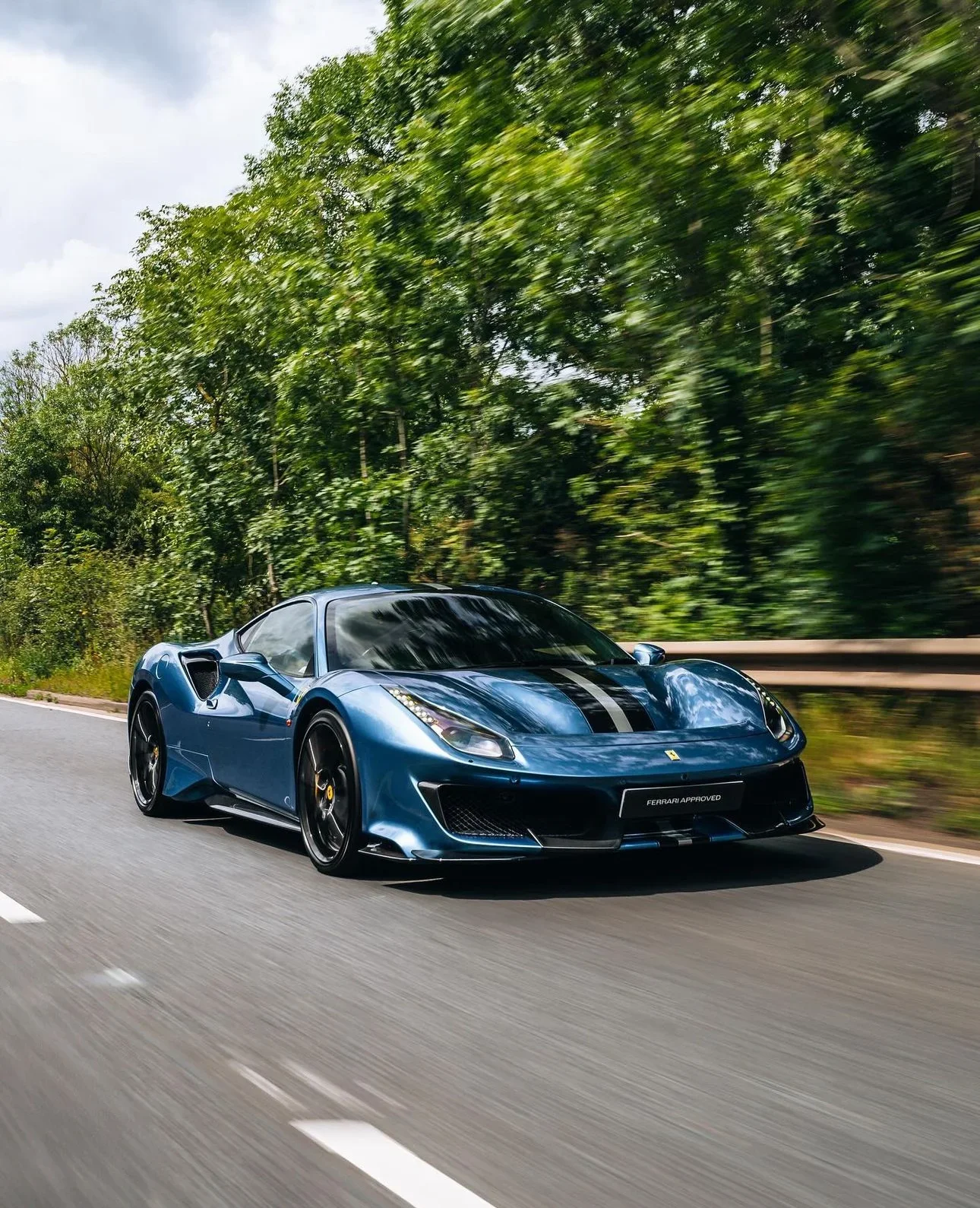 Ferrari 812 Superfast in Blue Pozzi — Driving on a tree-lined road — AKC Asset Management.