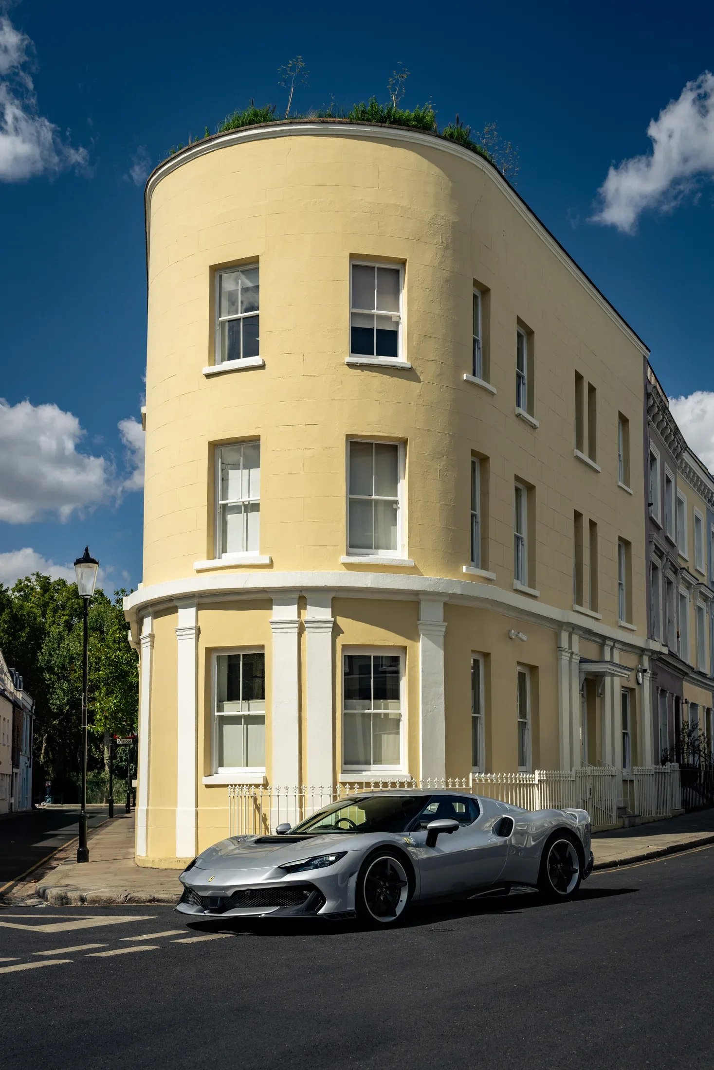 Ferrari 296 Speciale in Argento Nürburgring — Beside a curved corner building — AKC Asset Management.