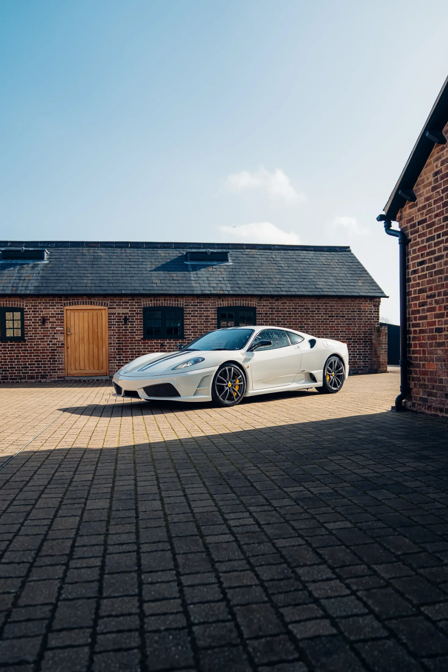 Ferrari 430 Scuderia in Bianco Avus — Side profile in a brick courtyard — AKC Asset Management.