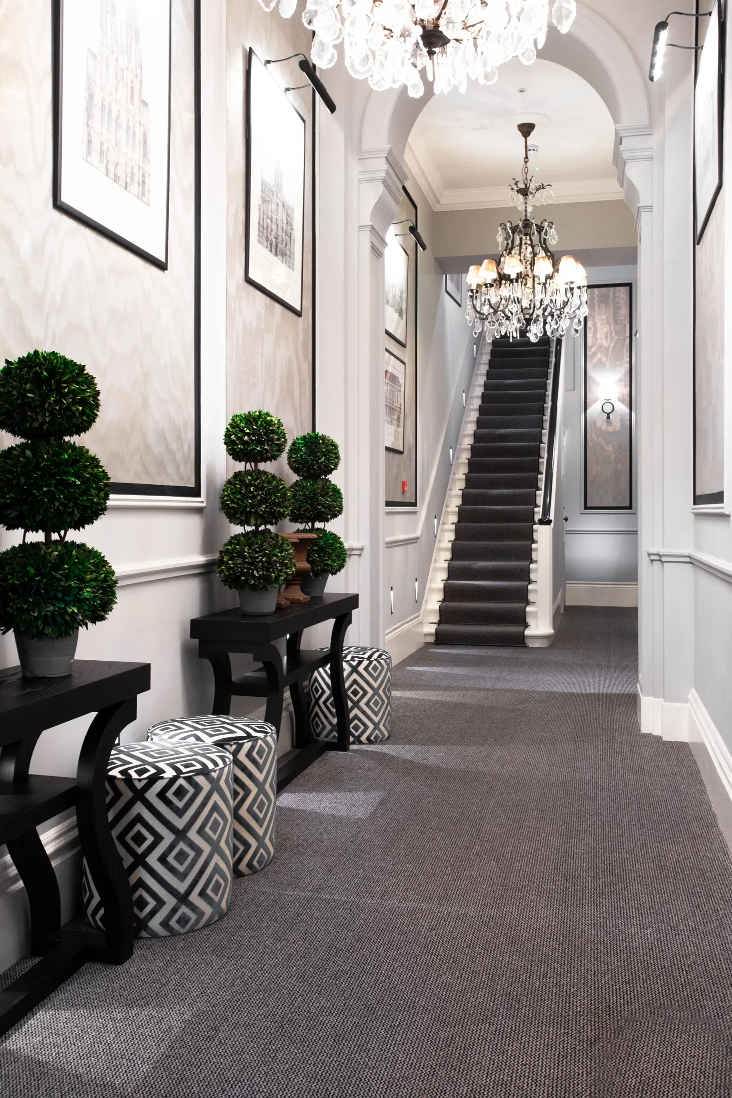 Entrance hall with a staircase, console tables and topiary — AKC Asset Management real estate, part of AKC Group.