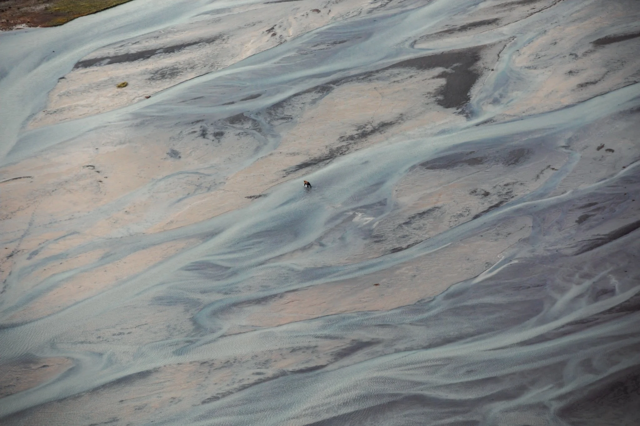 An aerial view of a glacier with a person walking on its icy surface.