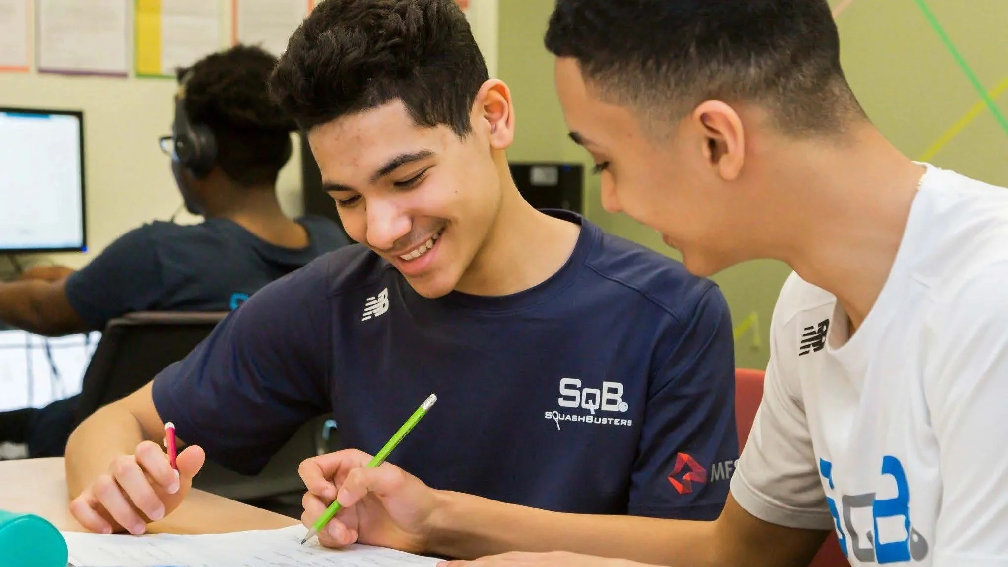 Two young men working together on a written assignment in a classroom setting.