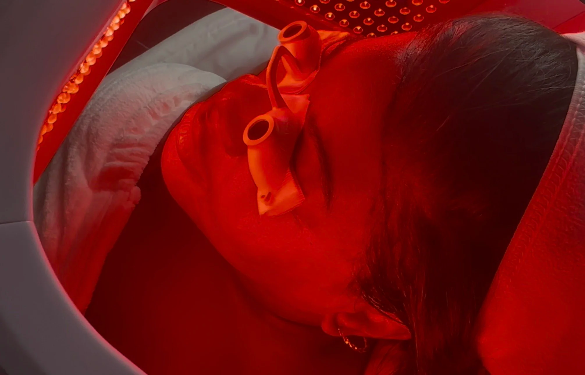 A person lying on an MRI table, covered with a red blanket, inside a medical scanning machine.