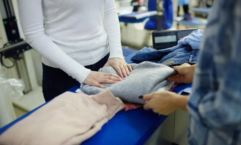Wash and fold laundry service with freshly cleaned clothes being folded for a customer.