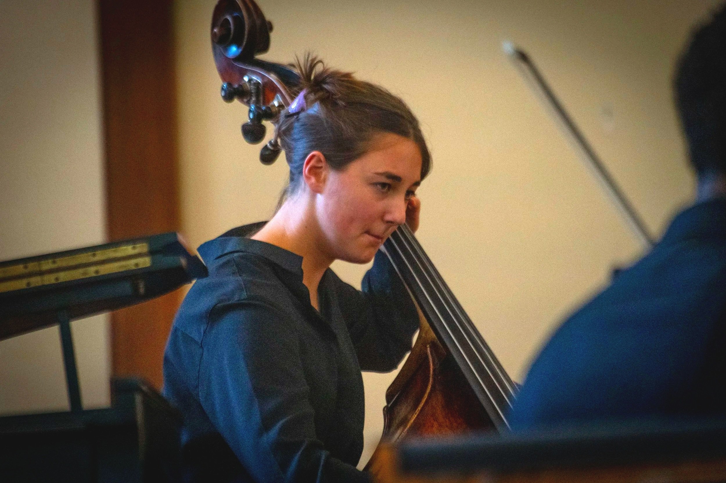 A woman playing a Double Bass in an indoor setting.