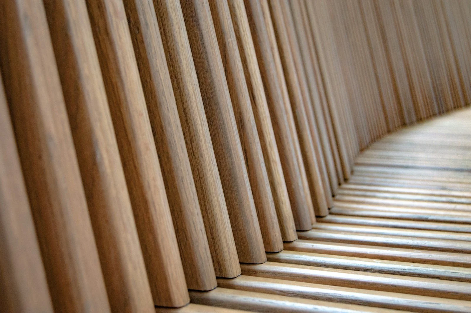 A close view of repeated timber slats forming a curved seating detail.