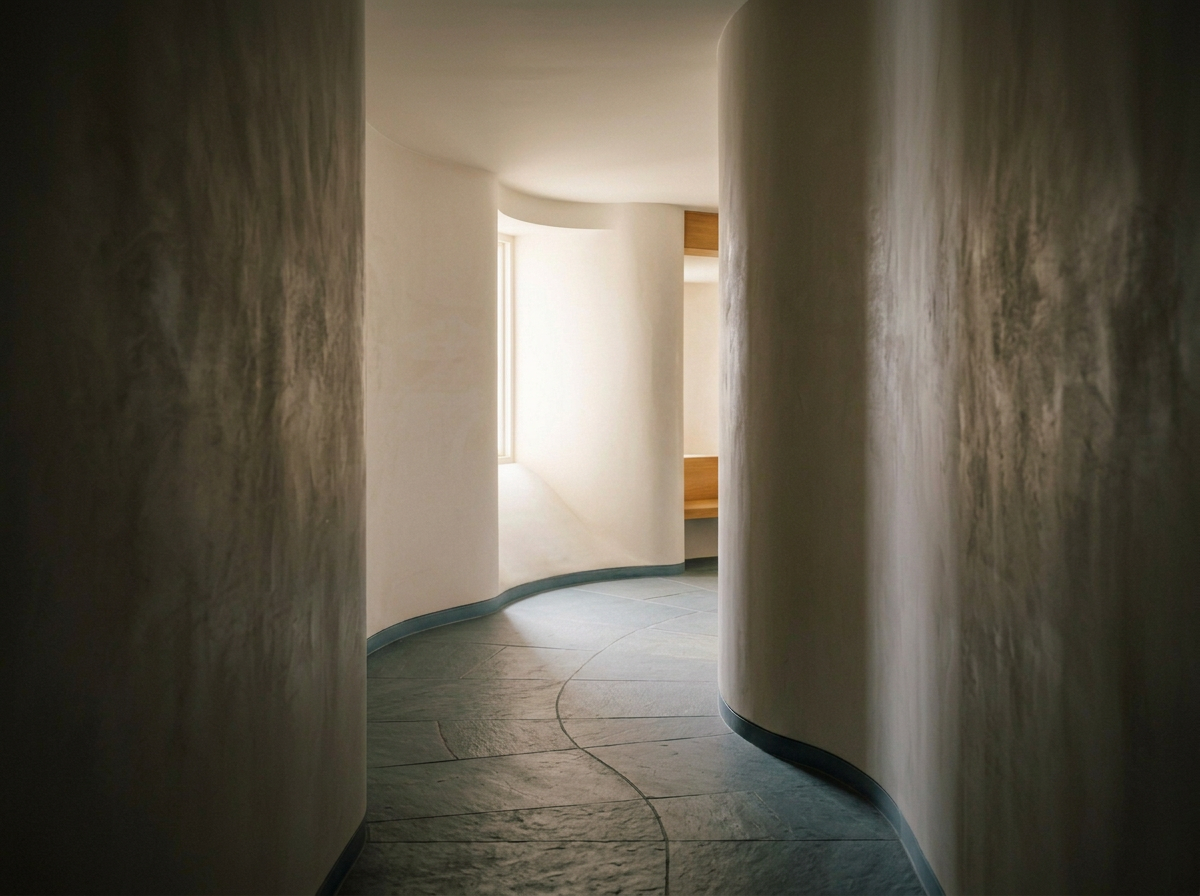 Contemporary hallway curving toward natural light, with warm-white walls and muted slate stone.