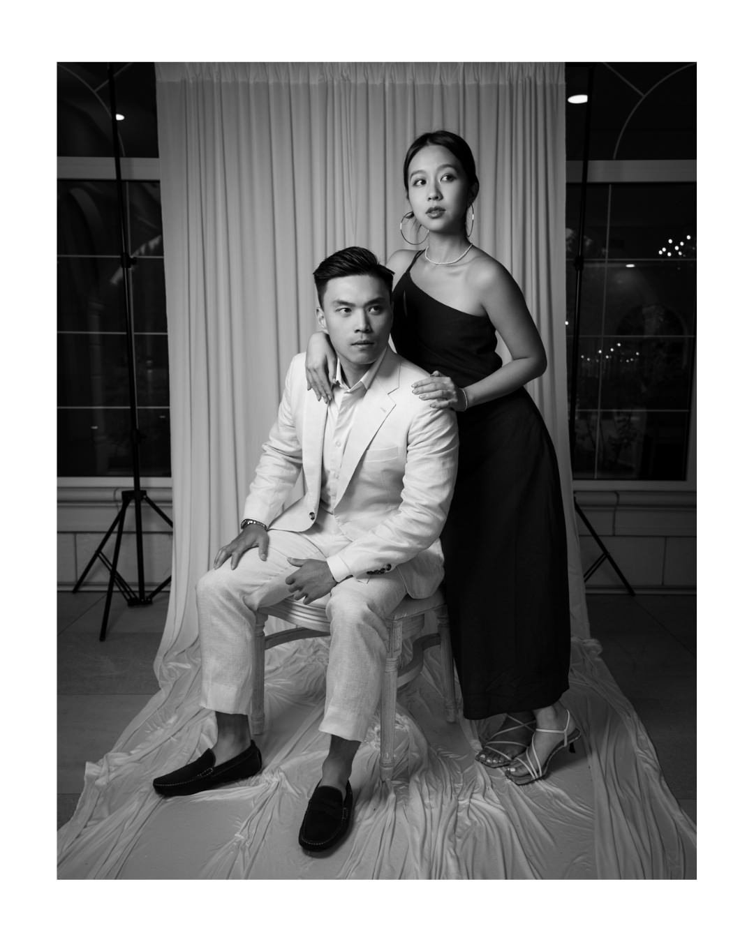 wedding guests pose for guest portraits in front of a white draped backdrop and stone archway.