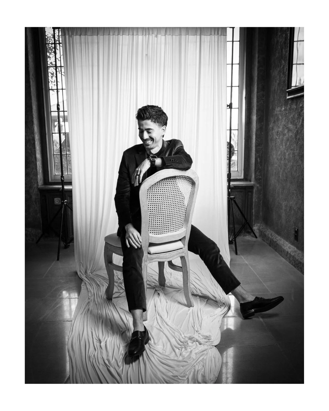 Smiling wedding guest seated backwards on a cane-back chair in a white draped portrait set at the Fairmont Banff Springs