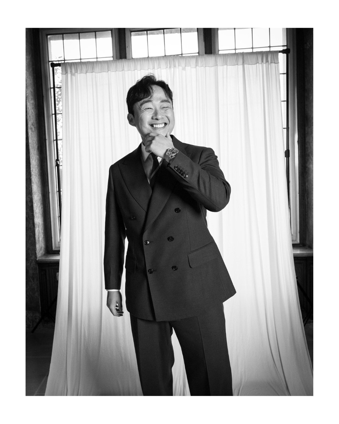 Smiling wedding guest in a suit posing in front of a draped backdrop