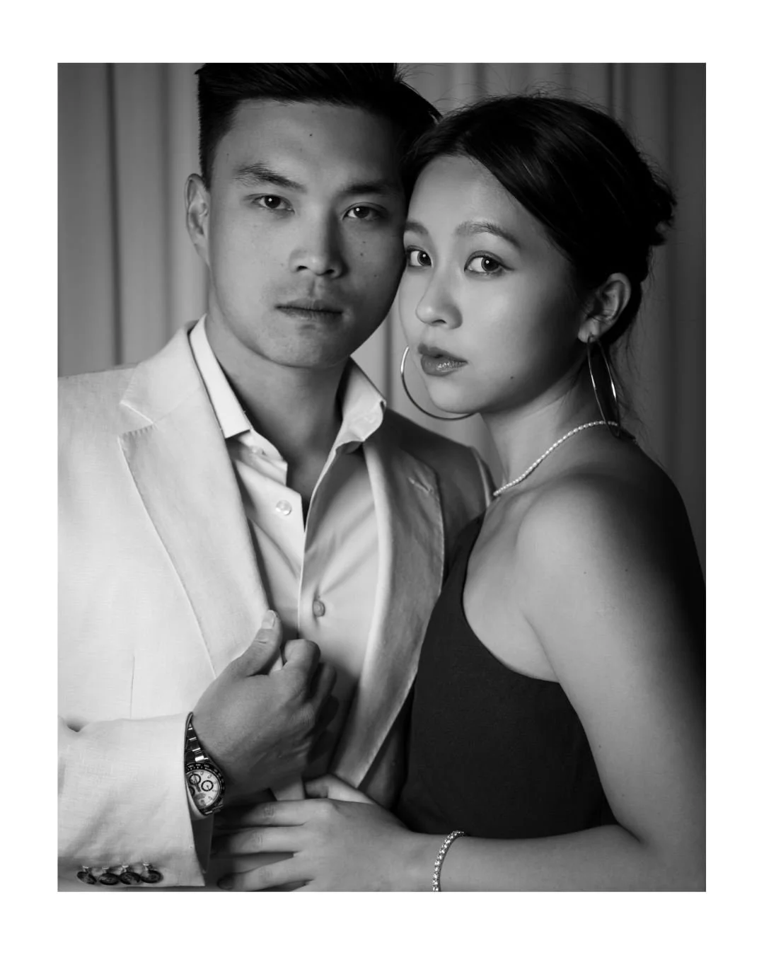 a couple pose for a black and white portrait against a white draped backdrop at archway manor in alberta