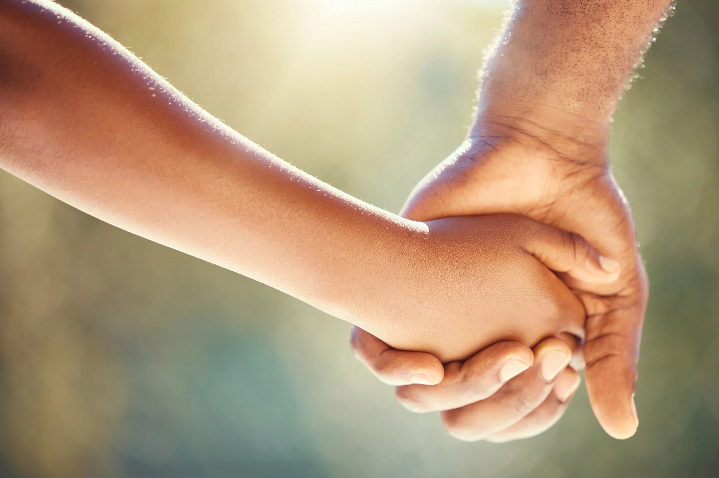 An adult hand and a child's hand holding each other