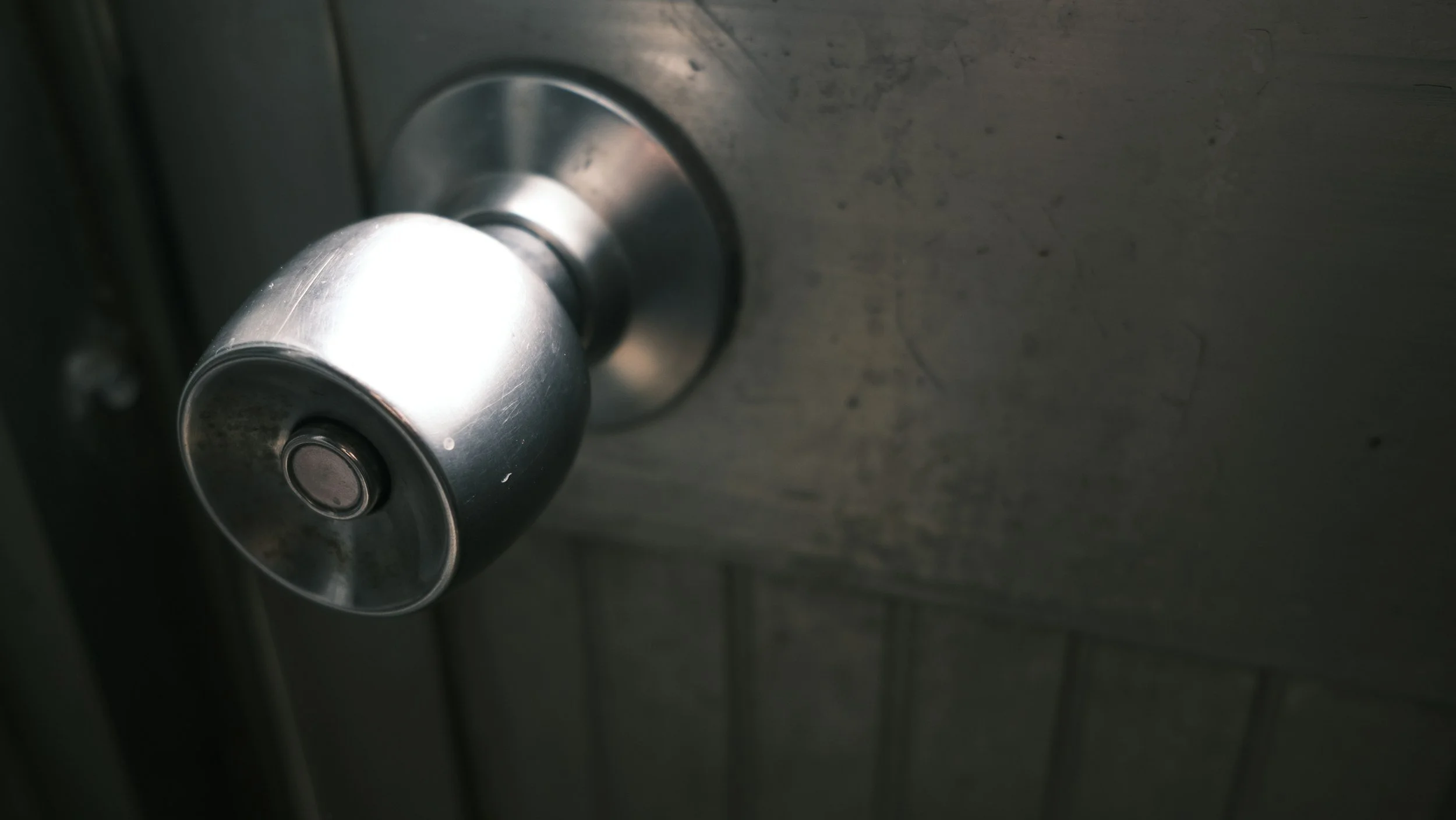 Close-up of a silver door knob and latch on a metal door.