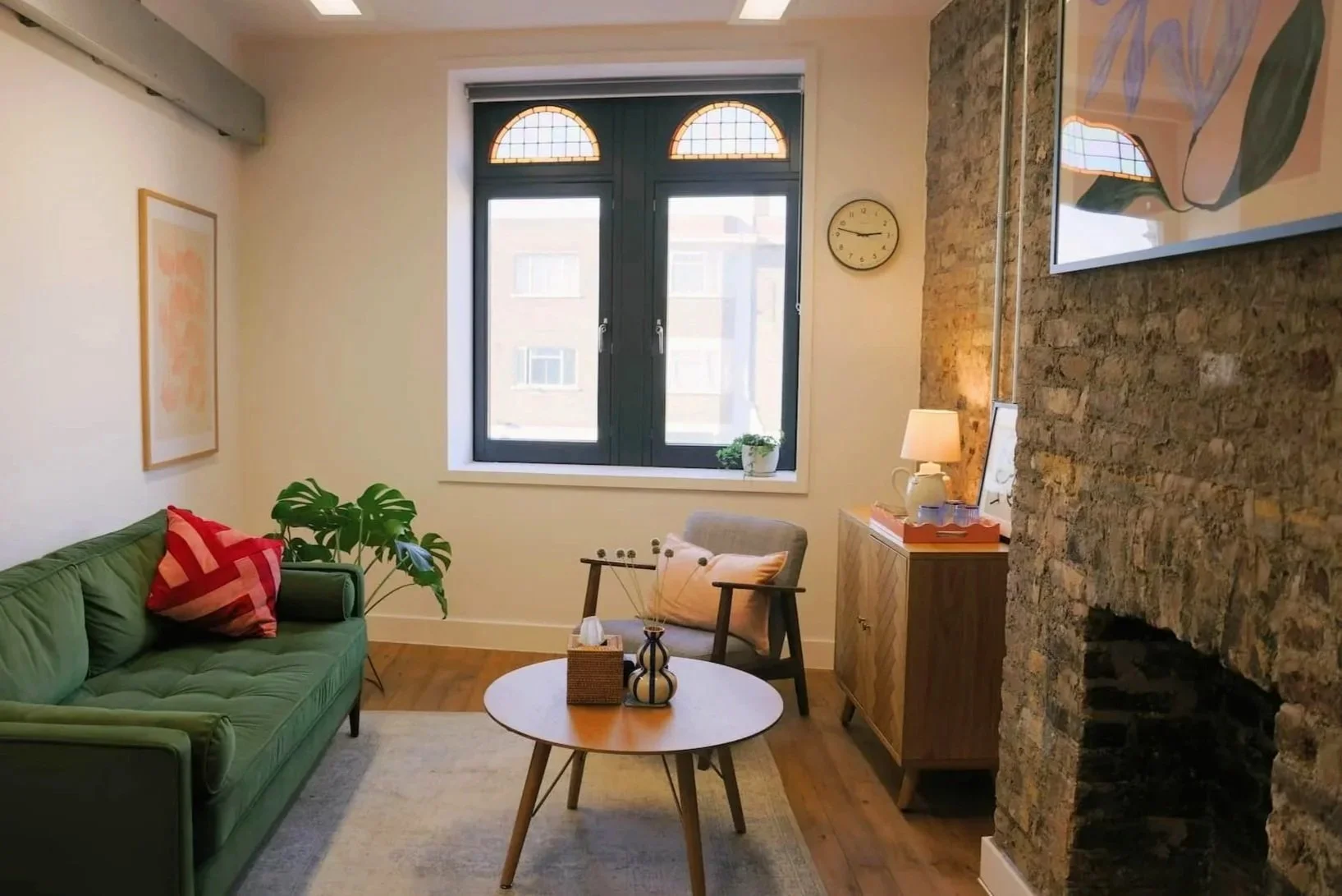 therapy room interior at Carlton Mansion in Brixton, with dark green sofa, bright open space with explosed brick walls