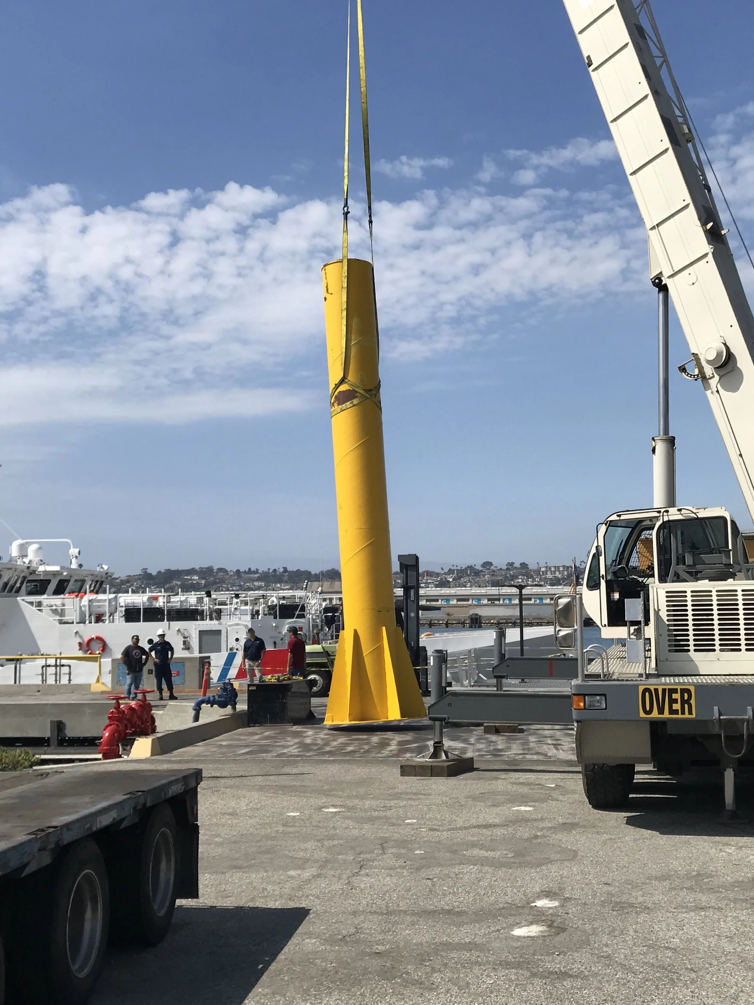 Mobile crane setting the U.S. Coast Guard crane mast upright at the pier
