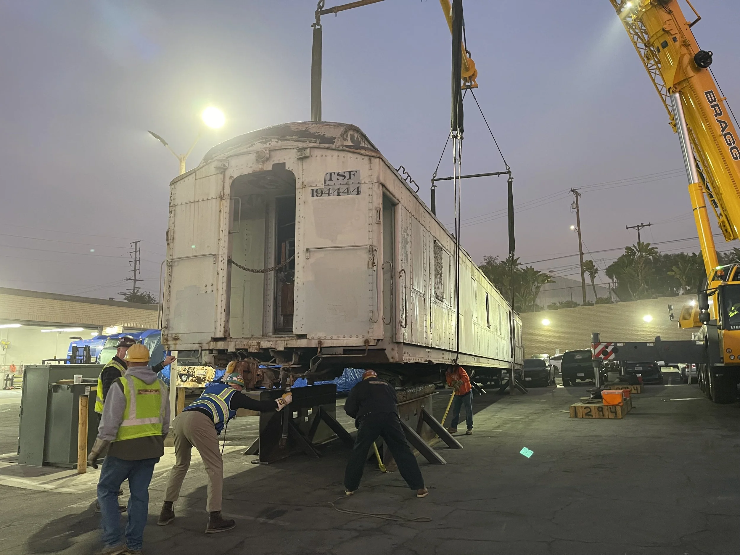 Crew positioning ATSF Santa Fe Railway car #194444 as a crane lifts it at night