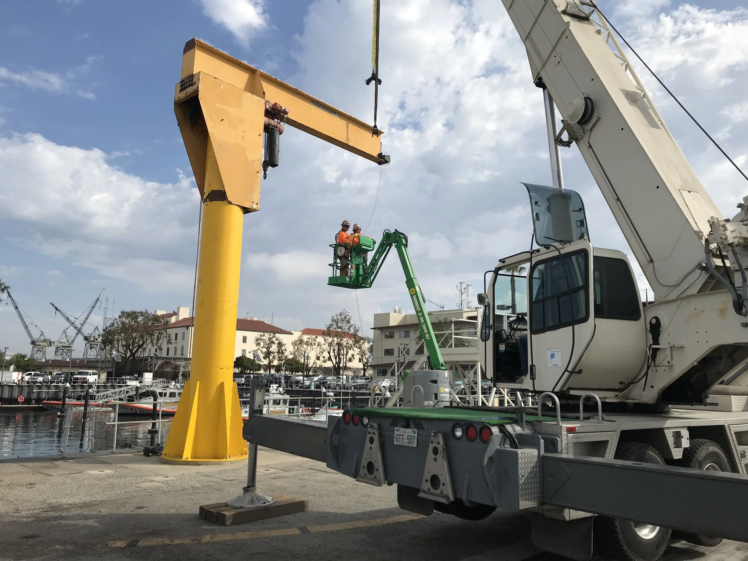Crew in a boom lift reinstalling the U.S. Coast Guard jib crane at the pier