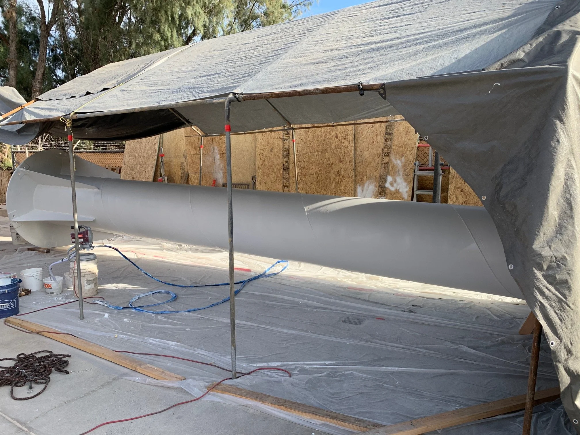 Steel crane jib in gray primer inside a covered work tent