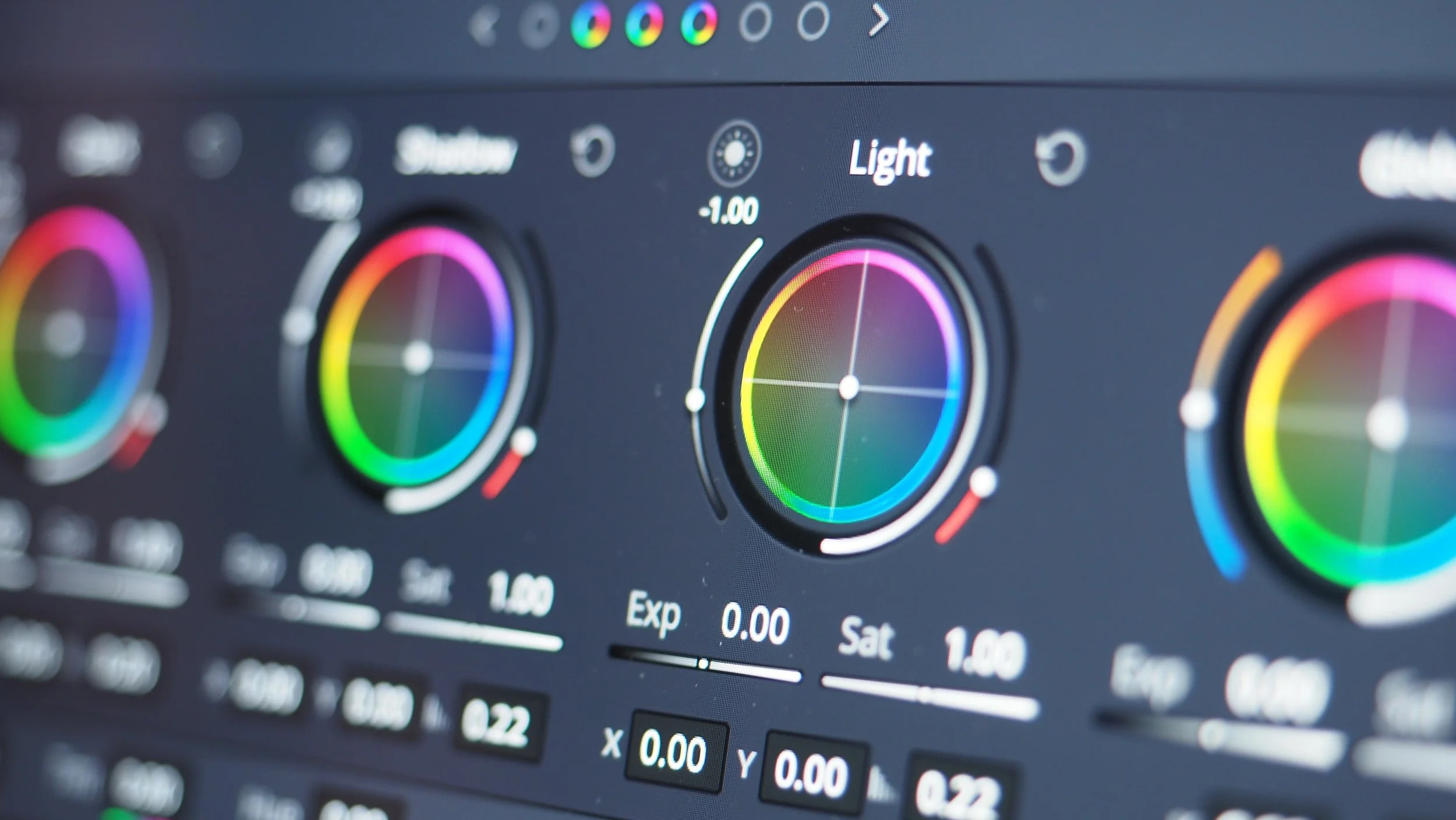 Close-up of a color grading software interface showing multiple color wheels and adjustment sliders for light and exposure.