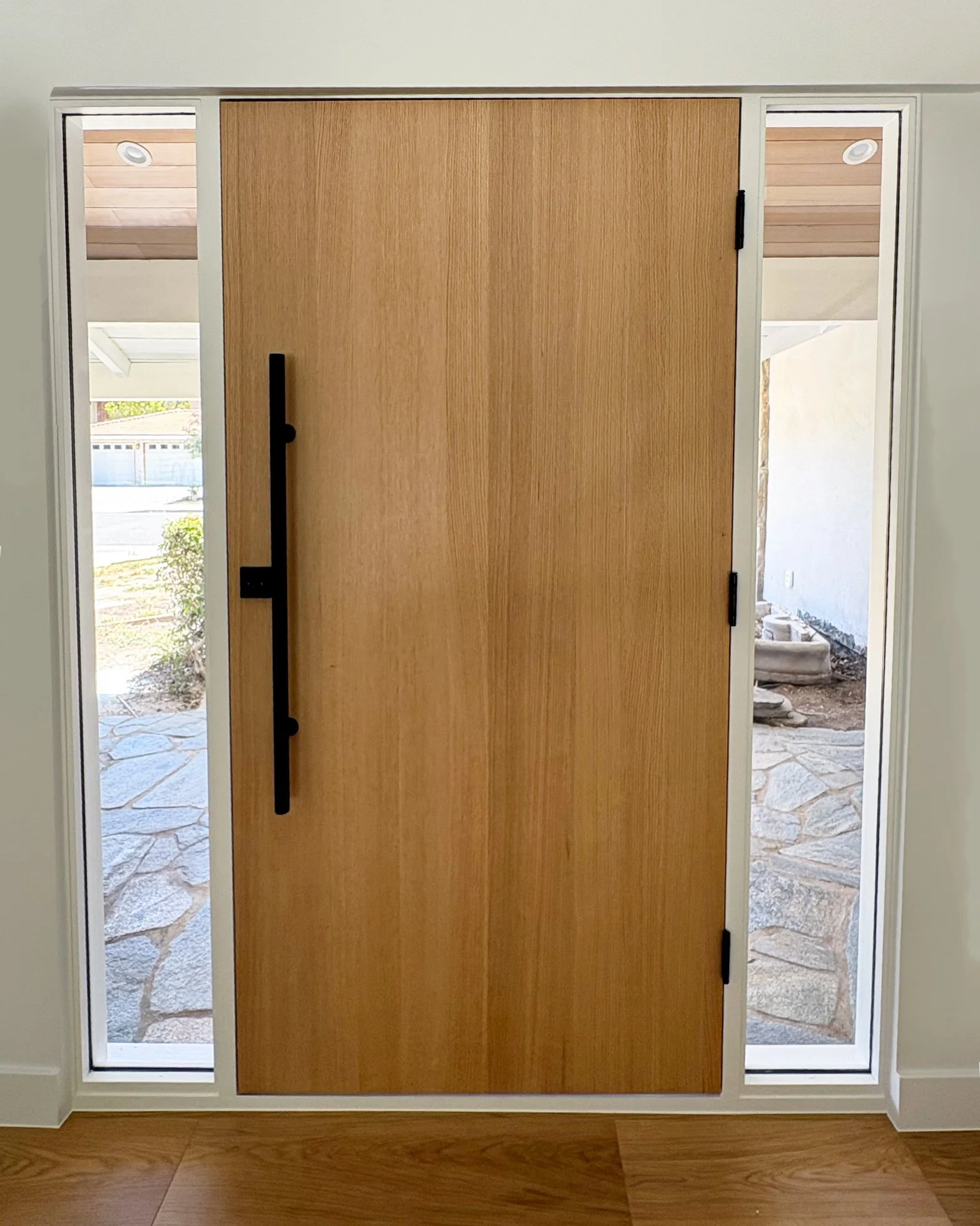 Renovated Westlake Residence entry featuring a natural oak front door, slim black handle and glass sidelights in Westlake Village.