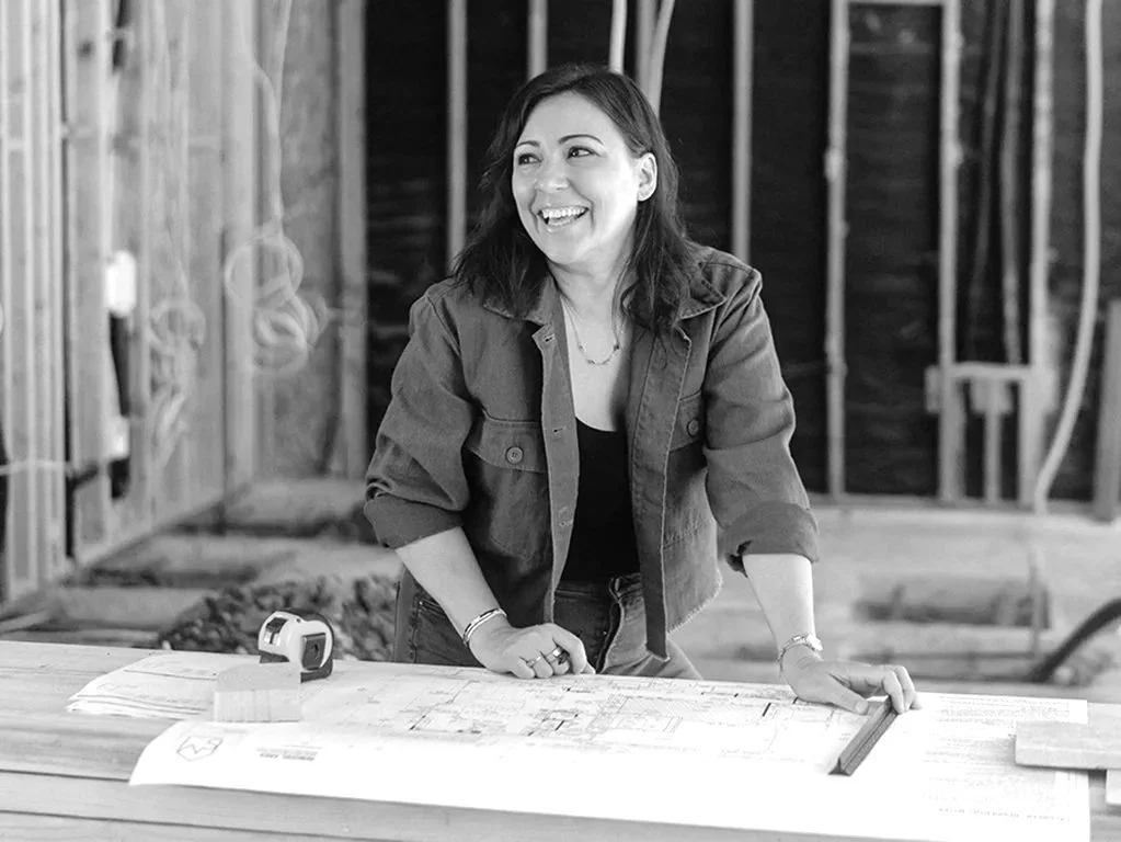 Sylvia Medrano reviewing plans at a residential construction site with exposed framing.