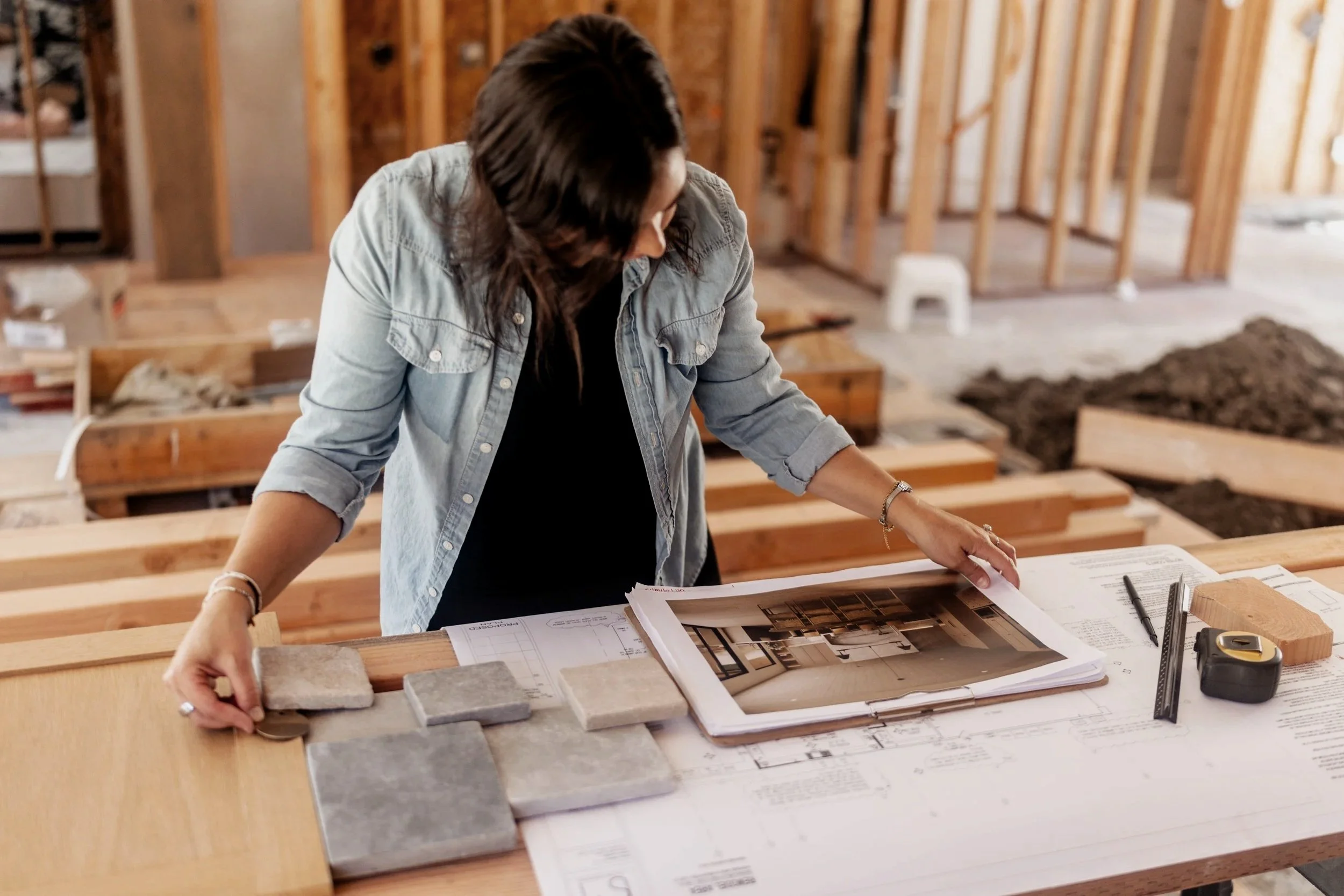 Sylvia Medrano reviewing architectural plans and material samples at a residential construction site.