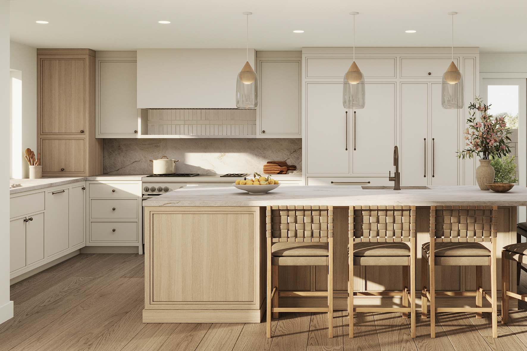 Modern kitchen with light wood cabinetry, a central island with a marble countertop, pendant lighting, a bowl of lemons, a vase with pink flowers, and bar stools with woven seats.