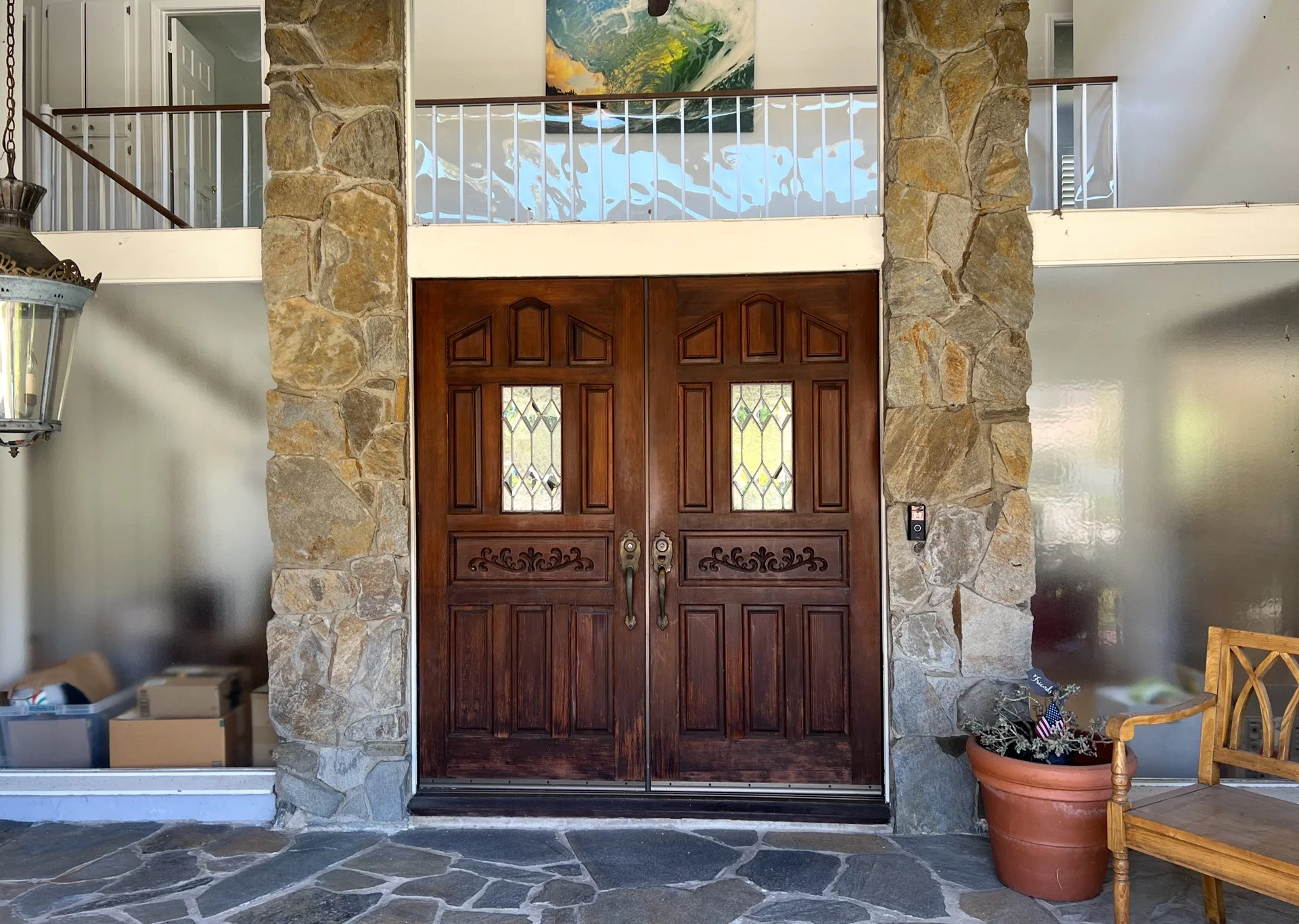 Original Westlake Residence entry before renovation, with carved wood double doors, stone columns and an upper-level railing.