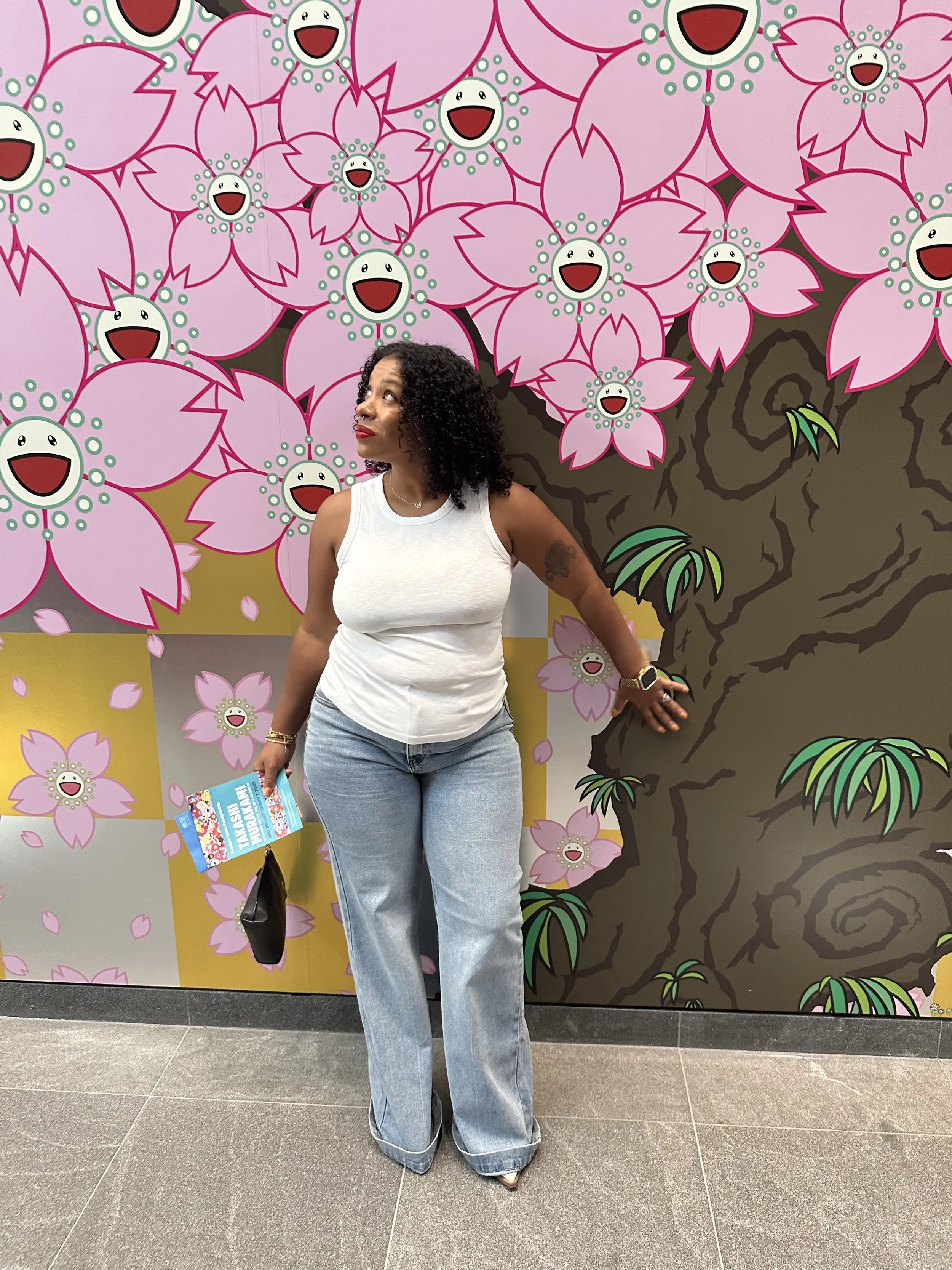 Vibes UnMatched founder standing in front of a colorful floral mural during a travel experience.