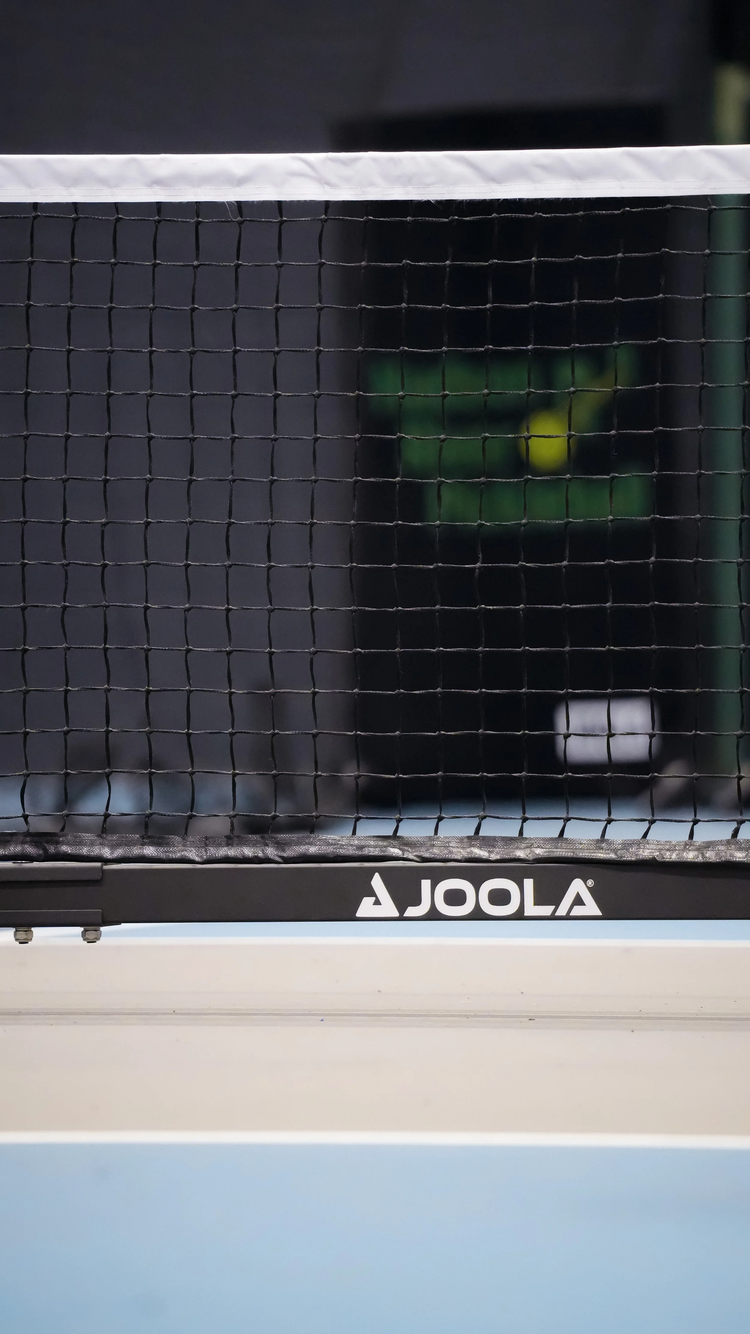 Close-up of a black Joola ping pong table with a net, with the background blurred.