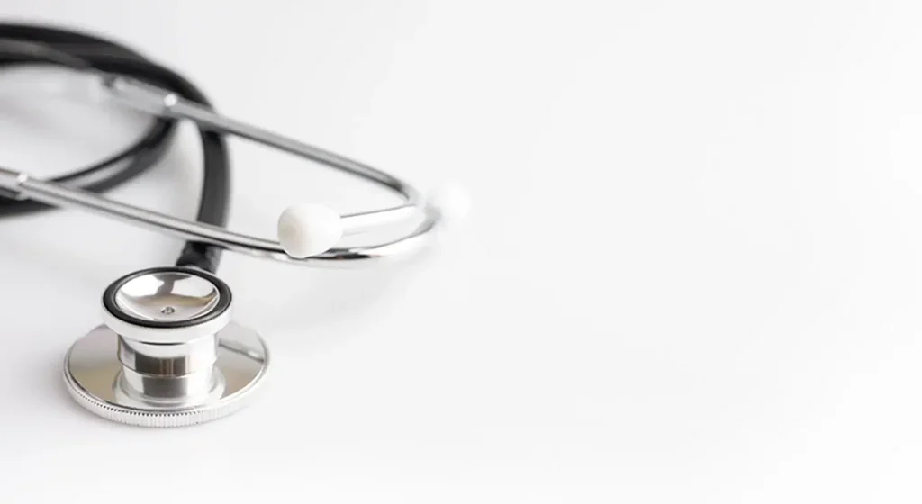 A stethoscope with a metallic chest piece and black tubing on a white surface.