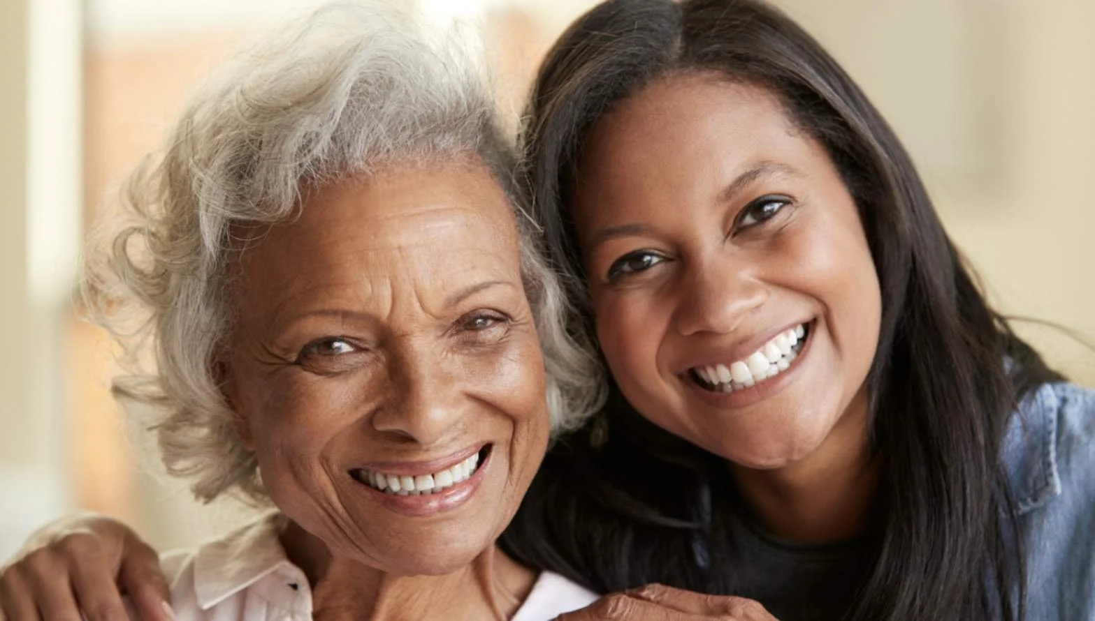 Smiling senior resident hugging her adult daughter during a visit at an assisted living facility.