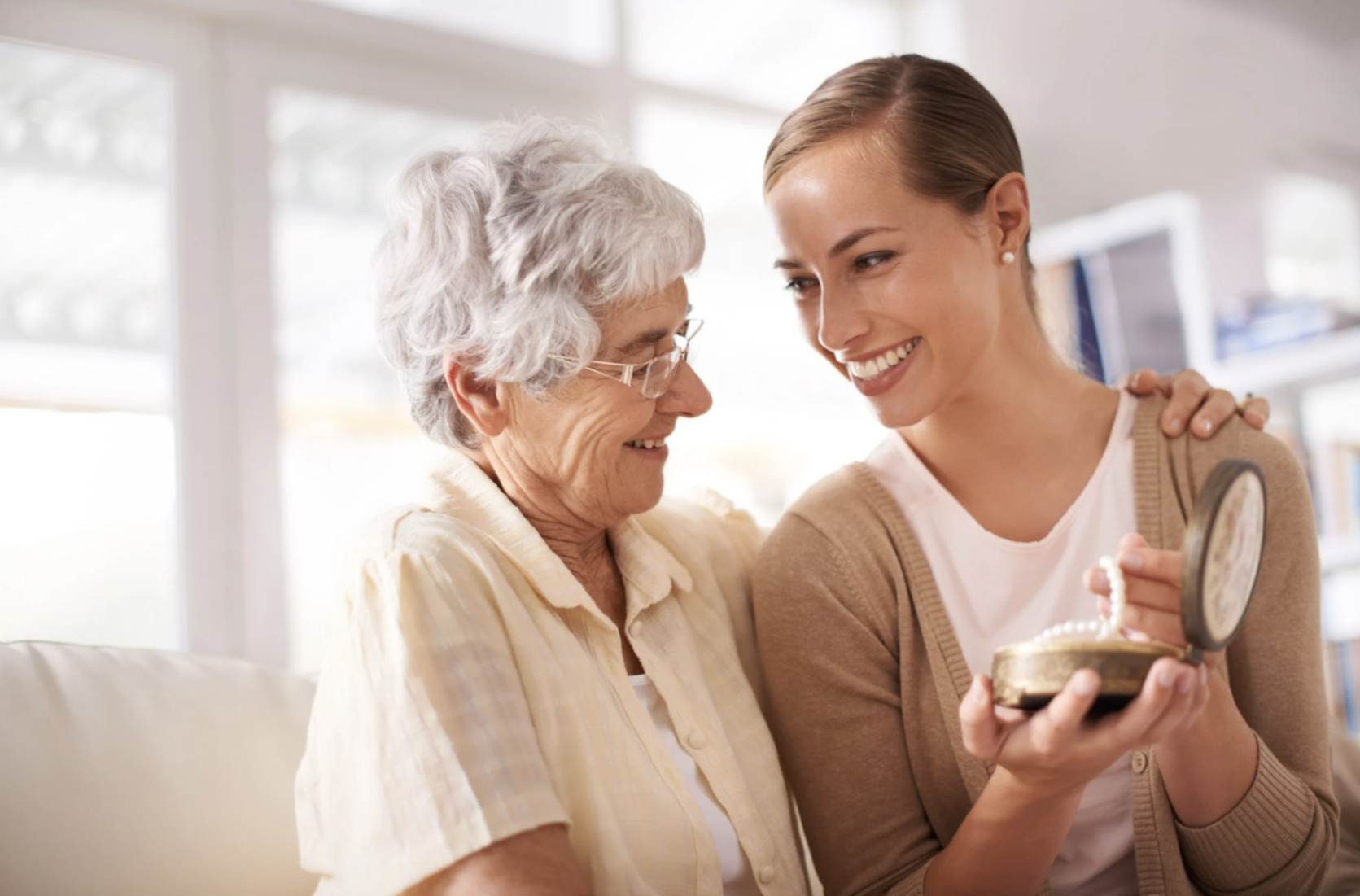 Caregiver engage in reminiscing therapy with an elderly woman looking through a sentimental keepsake box