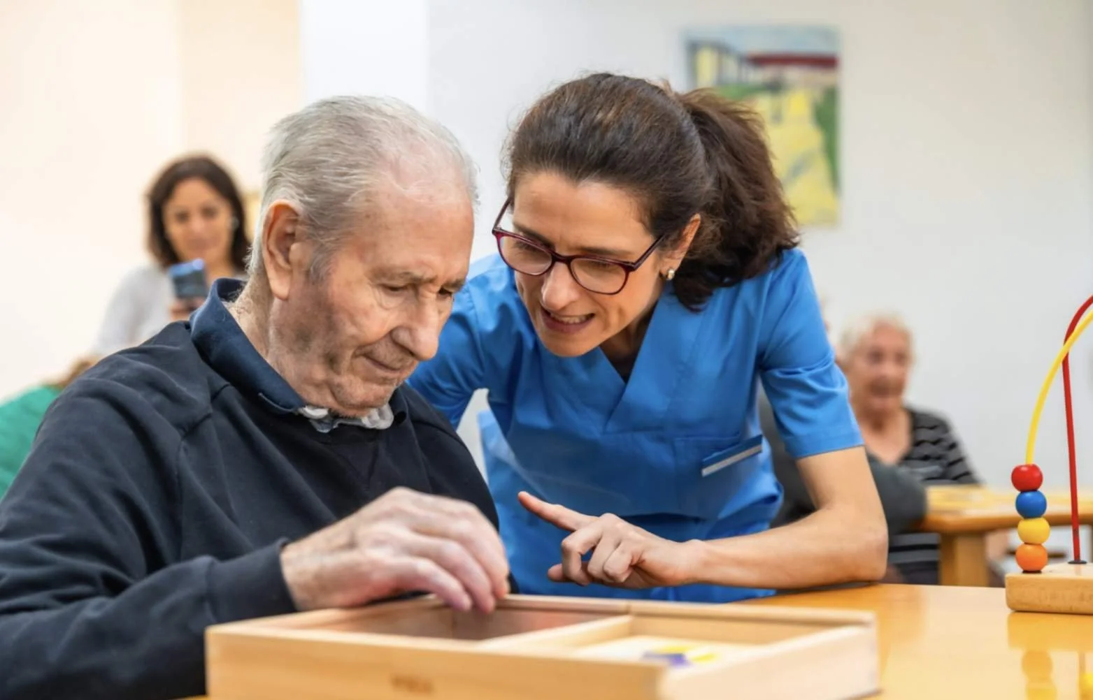 Memory care therapist assisting a senior man with cognitive therapy exercises