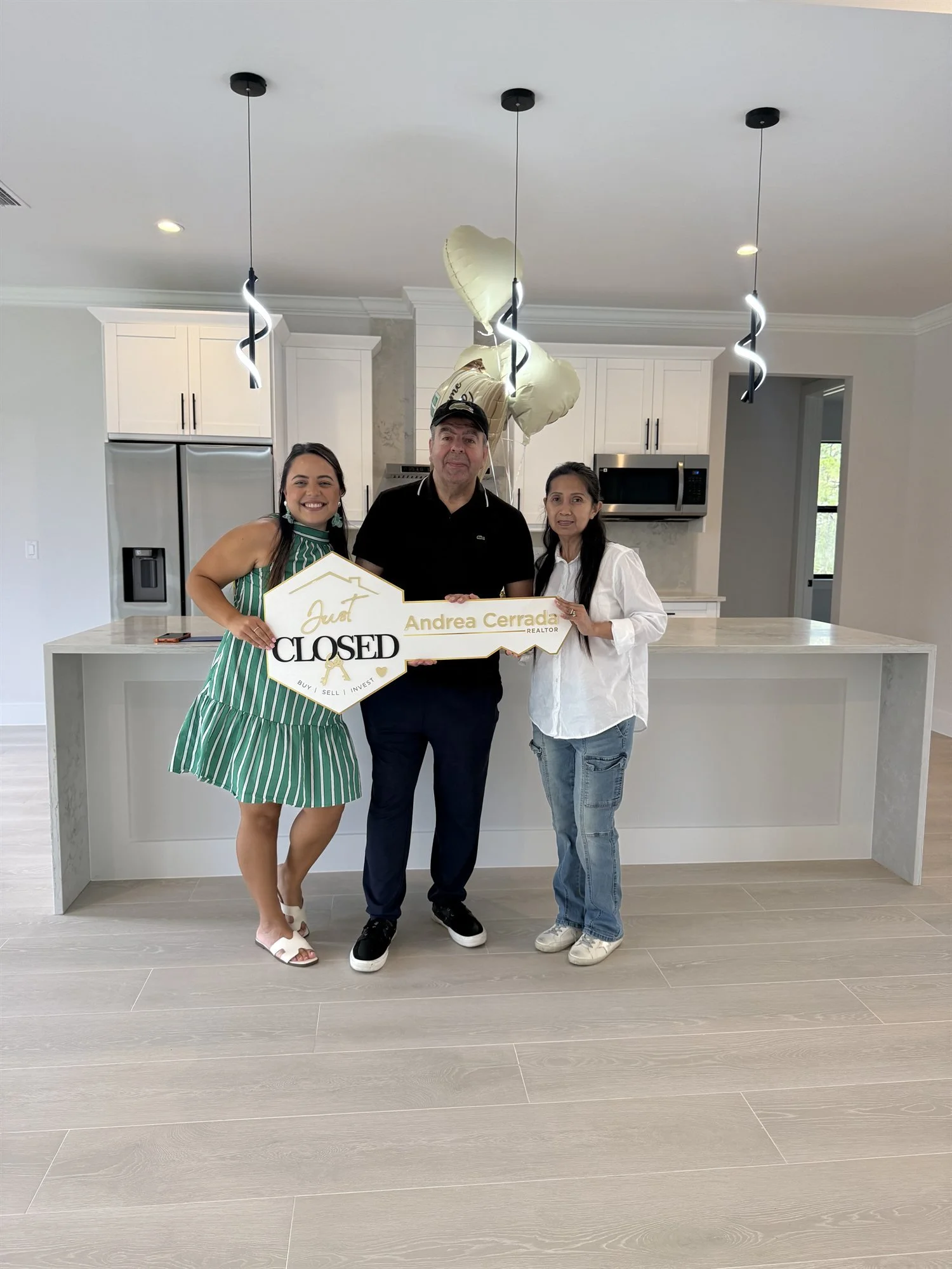 Andrea Cerrada with buyers holding a Closed sign in the kitchen of their new Naples home