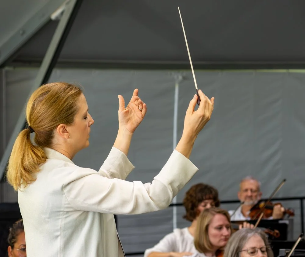 A female conductor leading an orchestra during practice or a performance.