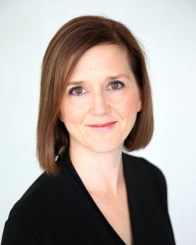 Headshot of Erin Freeman wearing a black top, smiling softly against a light background.